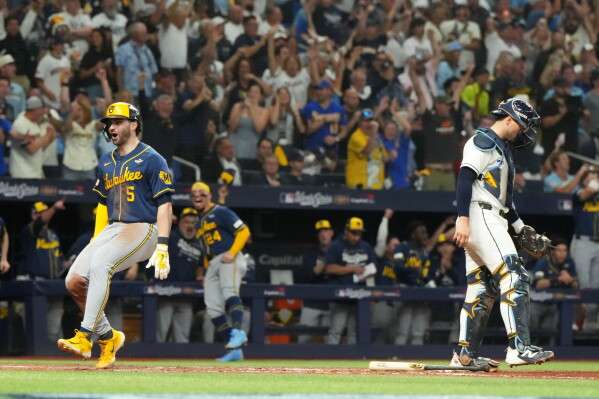 Milwaukee Brewers' Garrett Mitchell, left, celebrates past Tampa Bay Rays catcher Nick Fortes after scoring during the fifth inning of Game 3 of baseball's World Series, Monday, Oct. 26, 2026, in St. Petersburg, Fla., between the Milwaukee Brewers and the Tampa Bay Rays. (AP Photo/Ashley Landis)