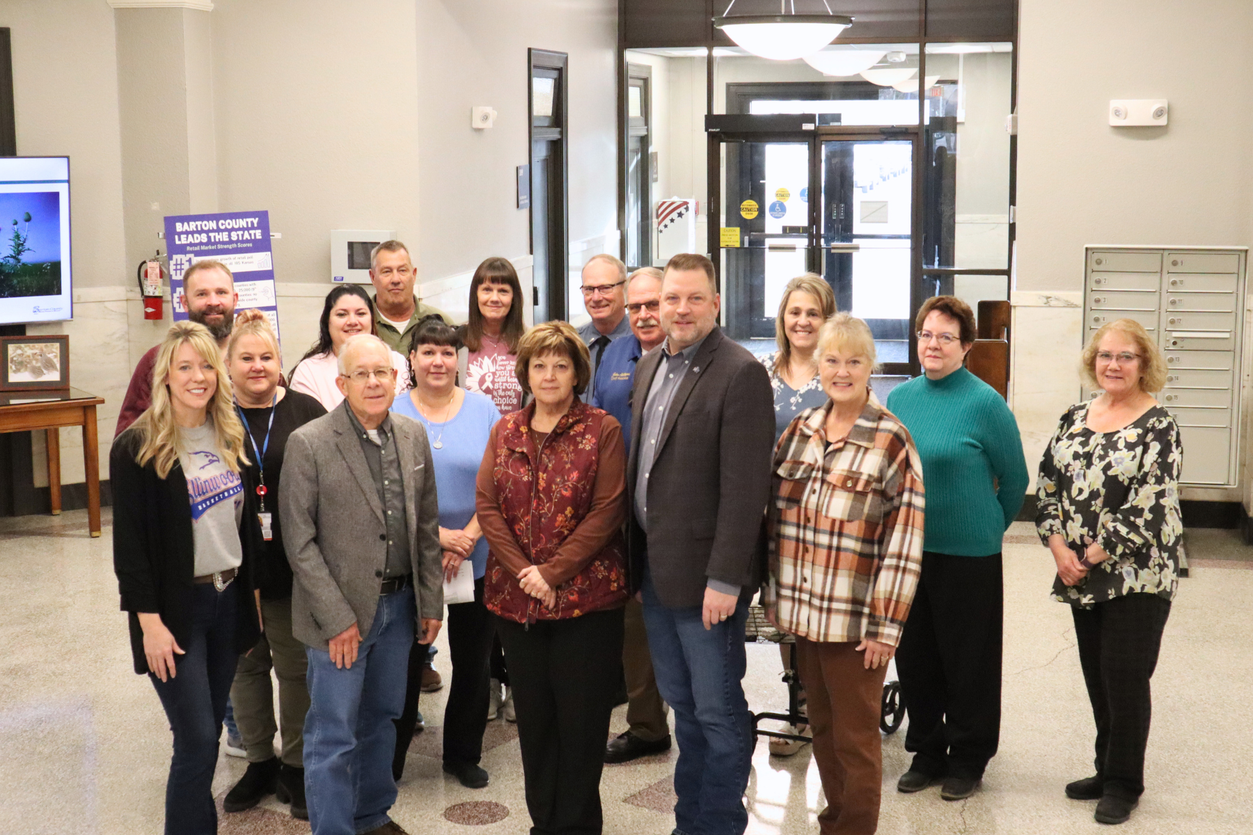 Barton County employees recognized for milestone years of service are pictured with members of the Barton County Commission in the courthouse rotunda, honoring decades of dedication and commitment to serving the community.