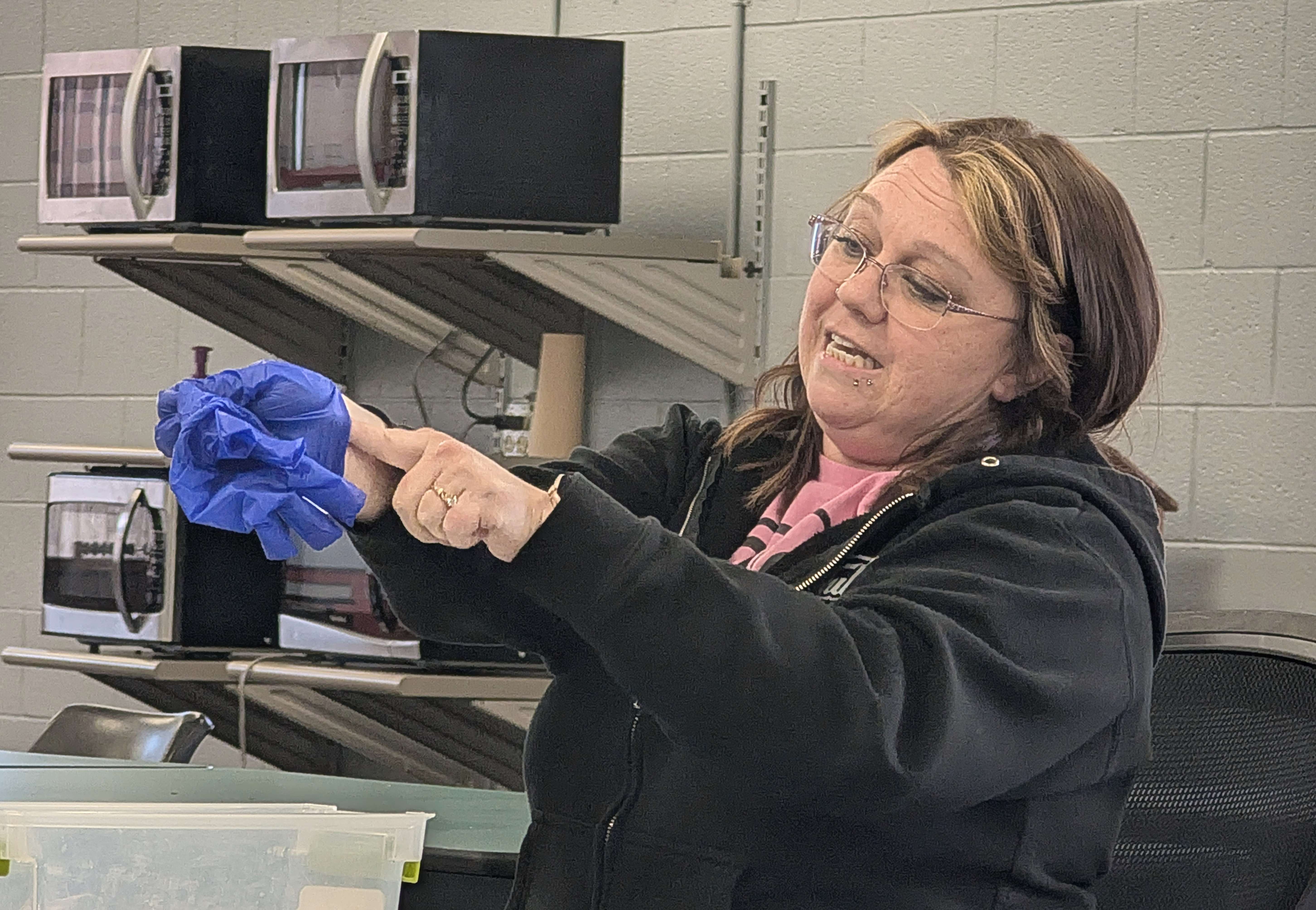 Bree Husted, environmental health and safety assistant at Fuller Industries Inc., demonstrates the proper way to remove gloves to avoid contamination in emergency situations. She gave the demonstration during first aide training Thursday afternoon.