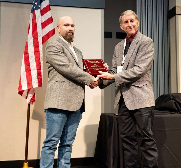 Chadron State College Professor and department chair Dr. Tony Perlinski, left, receives the 2025 Nebraska Range &amp; Conservation Endowment award from Loren Berger, President, Board of Directors, Nebraska Cattlemen Foundation on Dec. 11, 2025, in Kearney, Neb. (Photo Courtesy Nebraska Cattlemen, used with permission)
