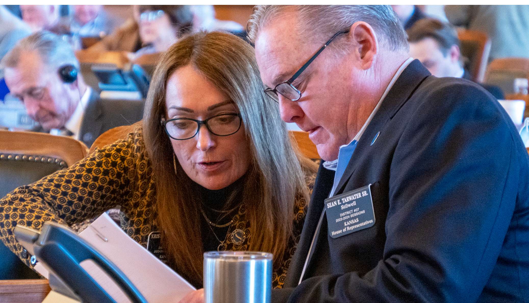  Republican Reps. Kristey Williams, of Augusta, and Sean Tarwater, of Stilwell, are on opposing sides of a bill to ban cellphones in all public and accredited nonpublic schools. They appear here on the House floor on April 6, 2023, in Topeka, Kansas. (Photo by Sherman Smith/Kansas Reflector)
