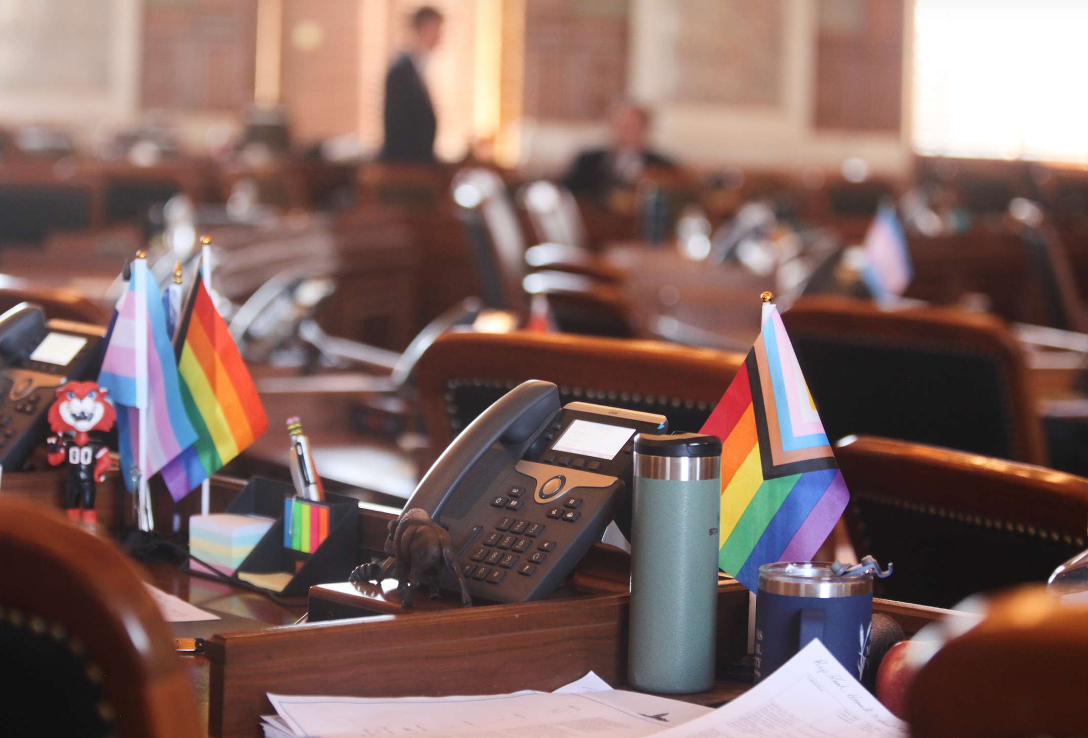 Small transgender and LGBTQ rights flags sit on the desks of Kansas state Reps. Tobias Schlingensiepen, right, D-Topeka, and Kirk Haskins, left, also D-Topeka, in the Kansas House chamber, protesting a new law that will prevent transgender people from changing their driver's licenses and birth certificates to reflect their gender identities and nullify past changes, Thursday, Feb. 19, 2026, at the Statehouse in Topeka, Kansas. (AP Photo/John Hanna)