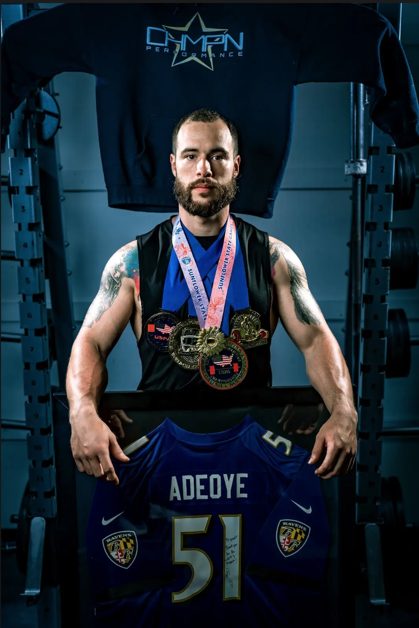 Matt Cookson holding up jersey of Aaron Adeoye, former Baltimore Ravens player in photoshoot. Cookson personally trained Adeoye before he played for the Ravens. Photo by WBC Visions