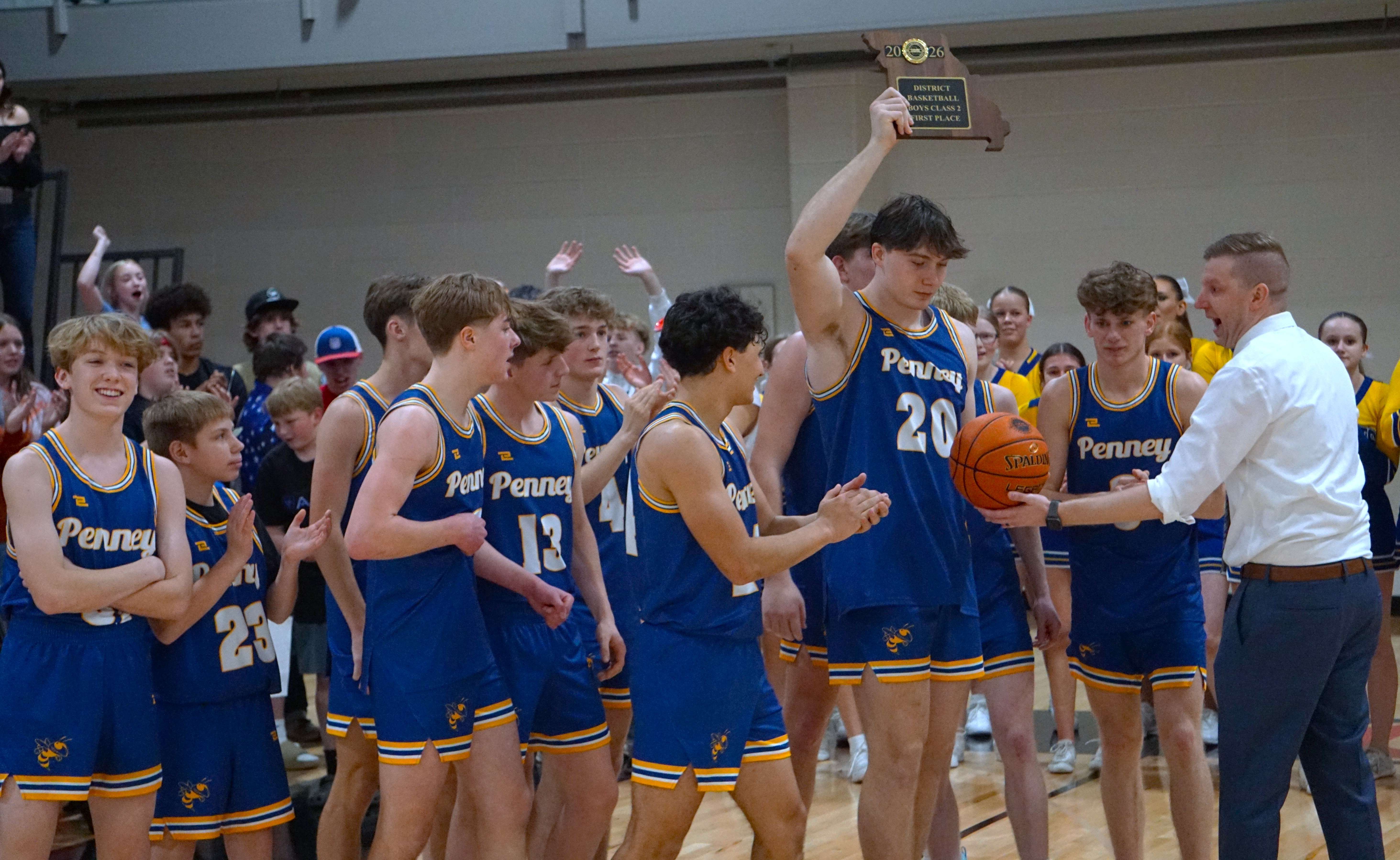 Jacob Miller hoists the trophy as the Penney Hornets won their first Class 2 District 16 title since 2016 and head coach Doug Burnett presents Miller with the game ball/ Photo by Matt Pike