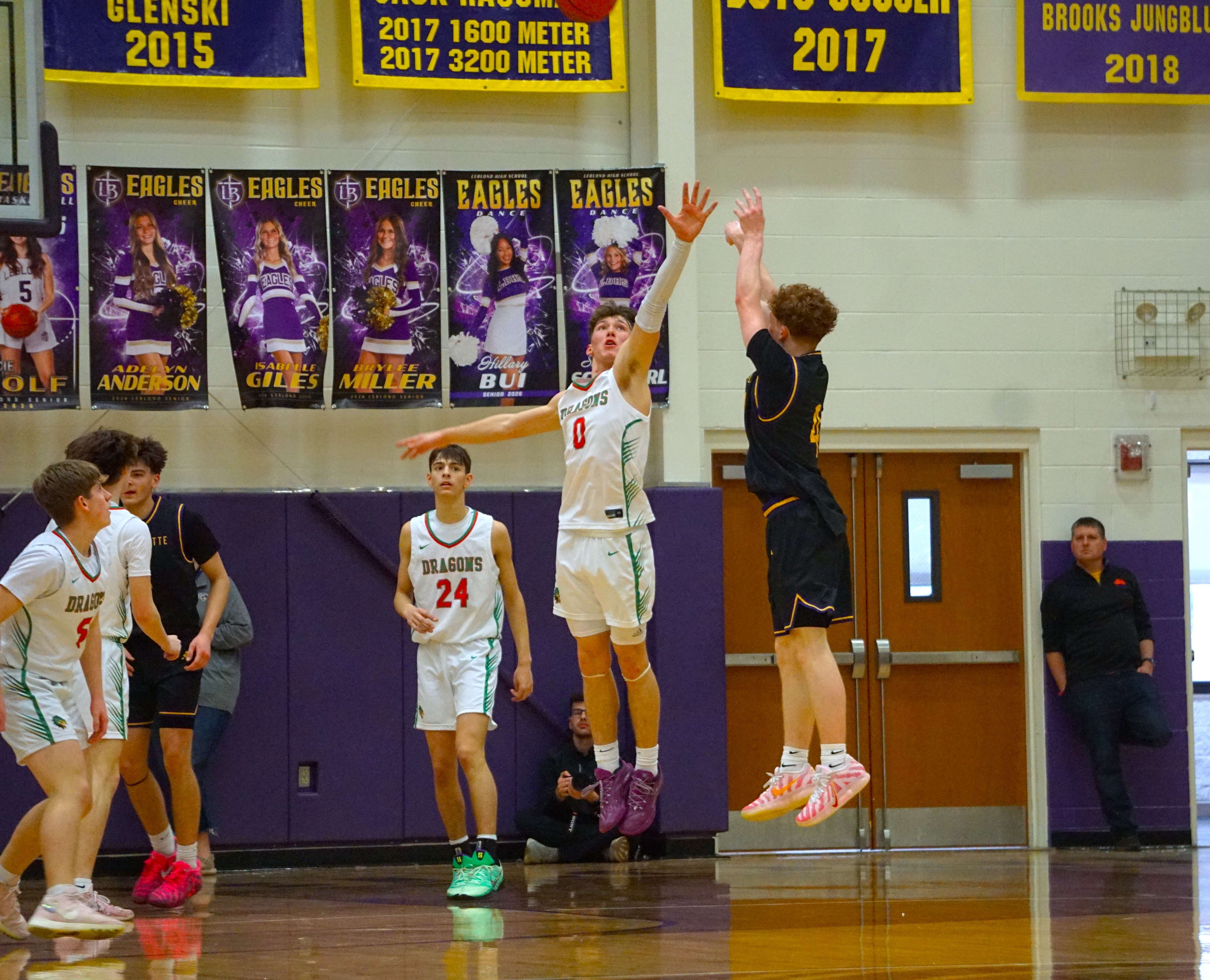 Jase Smith (4) shoots from beyond the arc against a defending Chris Kowalewycz (0)/ Photo by Matt Pike