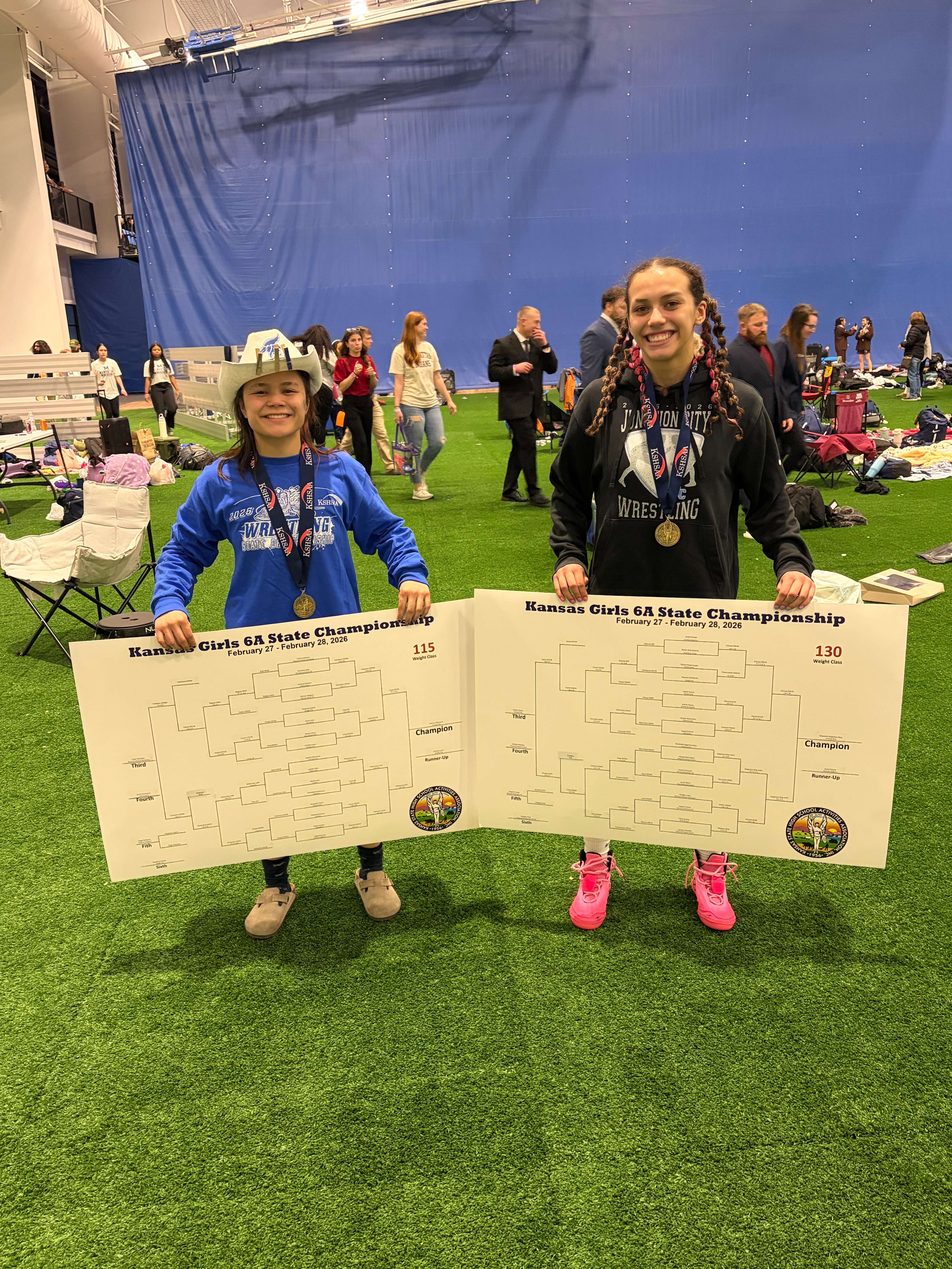 Junction City's Bree Villanueva and Elizabeth Edgerton-Diaz hold up their brackets after winning State in their weight classes.