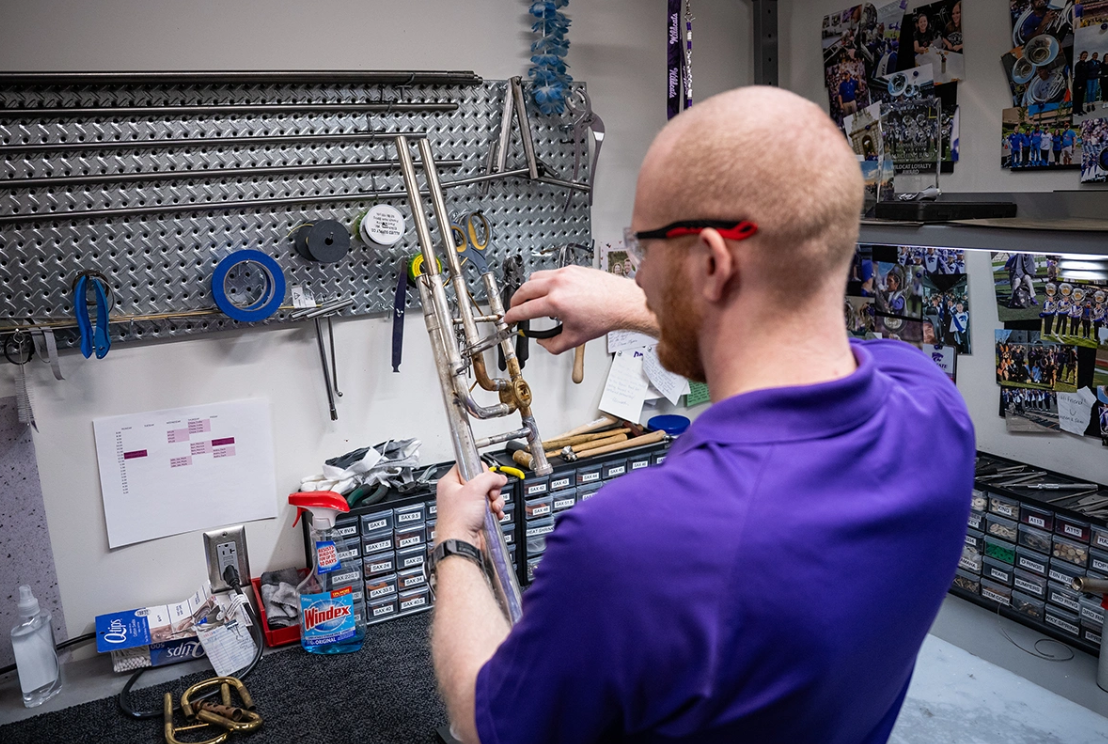 Colby Johnston checks the spacing on a brace he is using to repair a trombone.&nbsp;Photos by Jeff Moore/Kansas State University