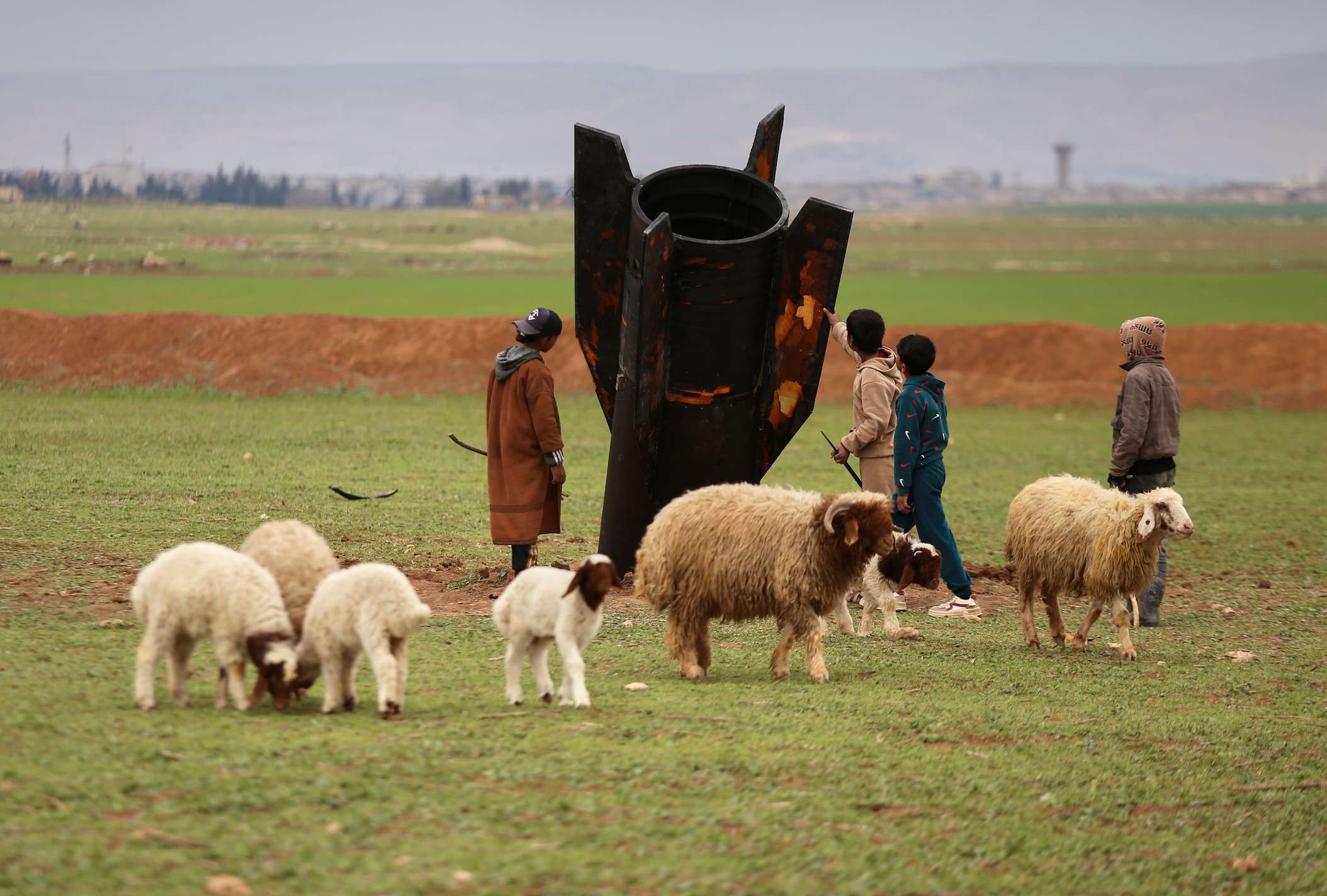 Exposing themselves to the danger of unexploded ordnance, shepherd boys inspect an unexploded Iranian projectile that landed in an open field on the outskirts of Qamishli, eastern Syria, Wednesday, March 4, 2026. (AP Photo/Baderkhan Ahmad)