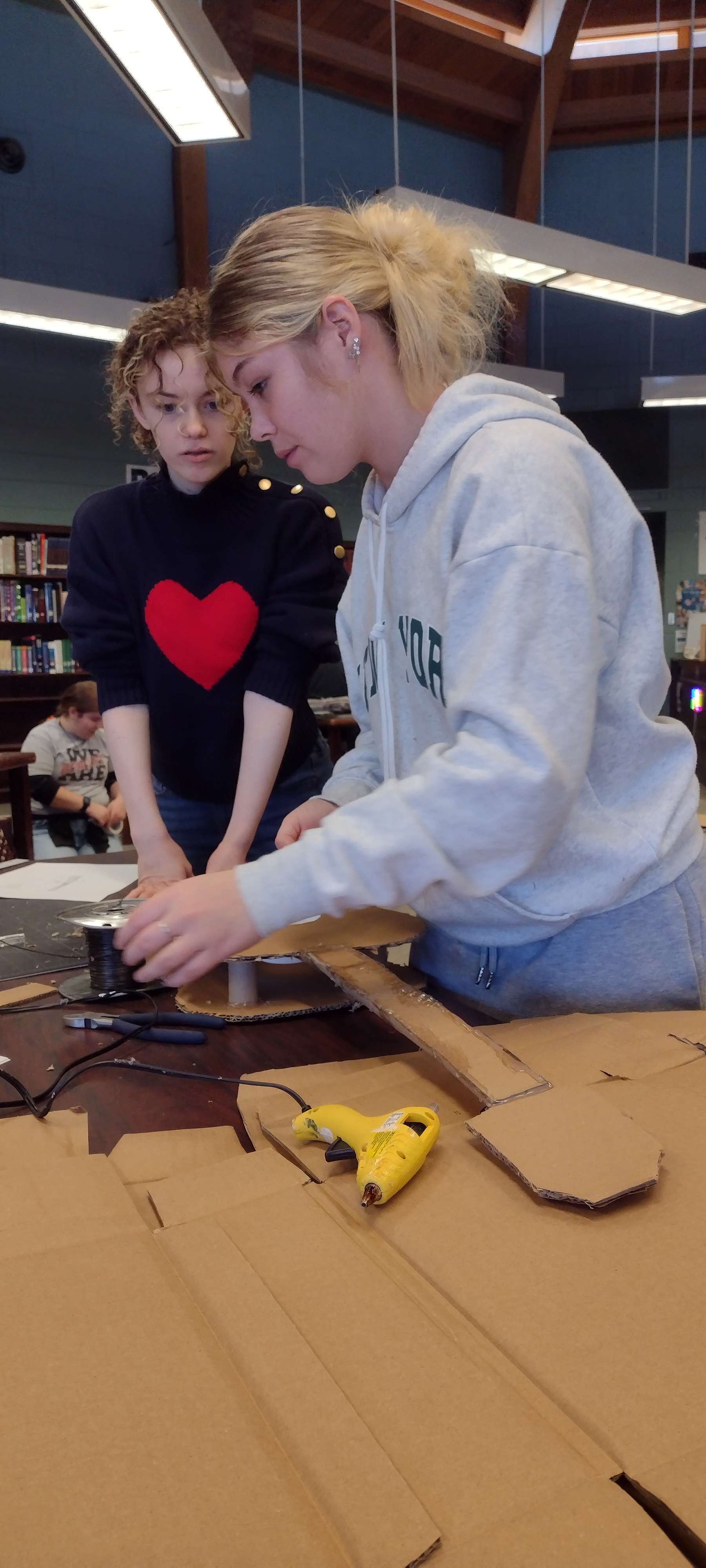 Two artists from Gordon-Rushville craft a cardboard guitar.
