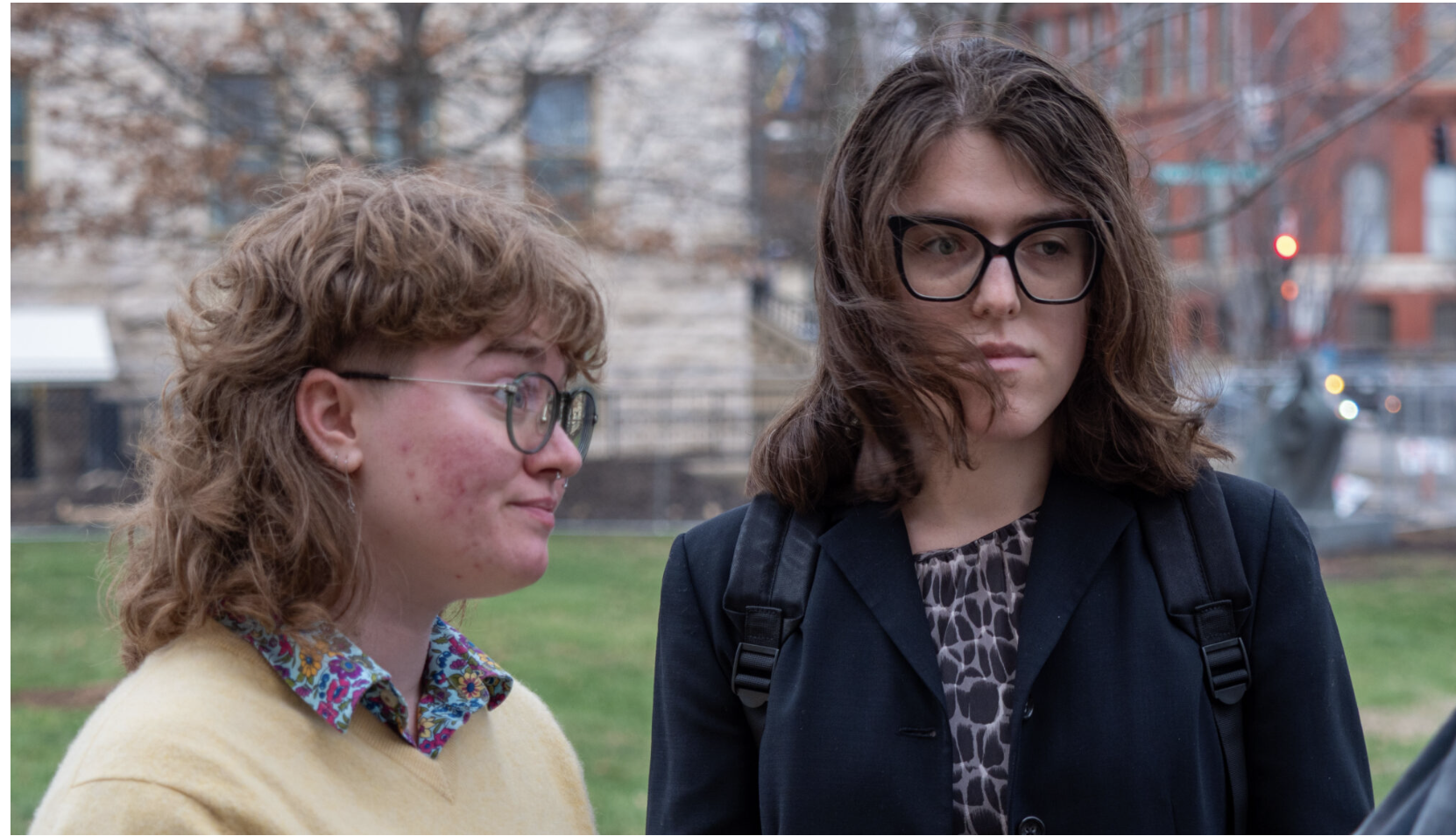 Z Kemp, left, and Avie Fallis attended a Douglas County District Court hearing March 6, 2026, about Kansas’ new law because it affects them and their loved ones. The law forces people to use the bathroom related to their biological sex at birth and to put that sex marker on their driver’s licenses and birth certificates. (Photo by Sherman Smith/Kansas Reflector)