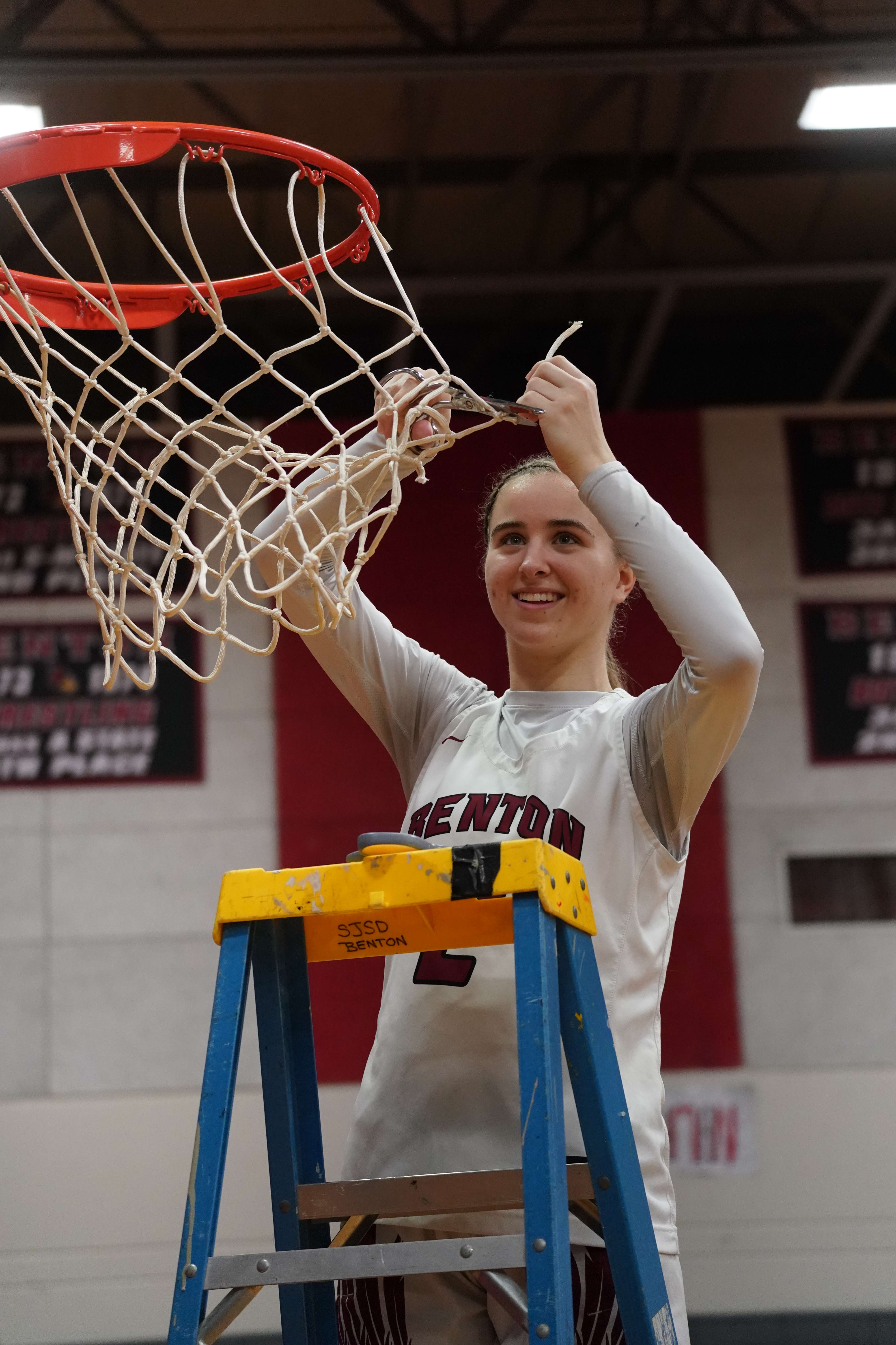 Senior Jerzey Ziolkowski cuts down part of the net after the Benton Cardinal girls won the Class 4 District 16 championship/ Photo courtesy of Clifton Grooms