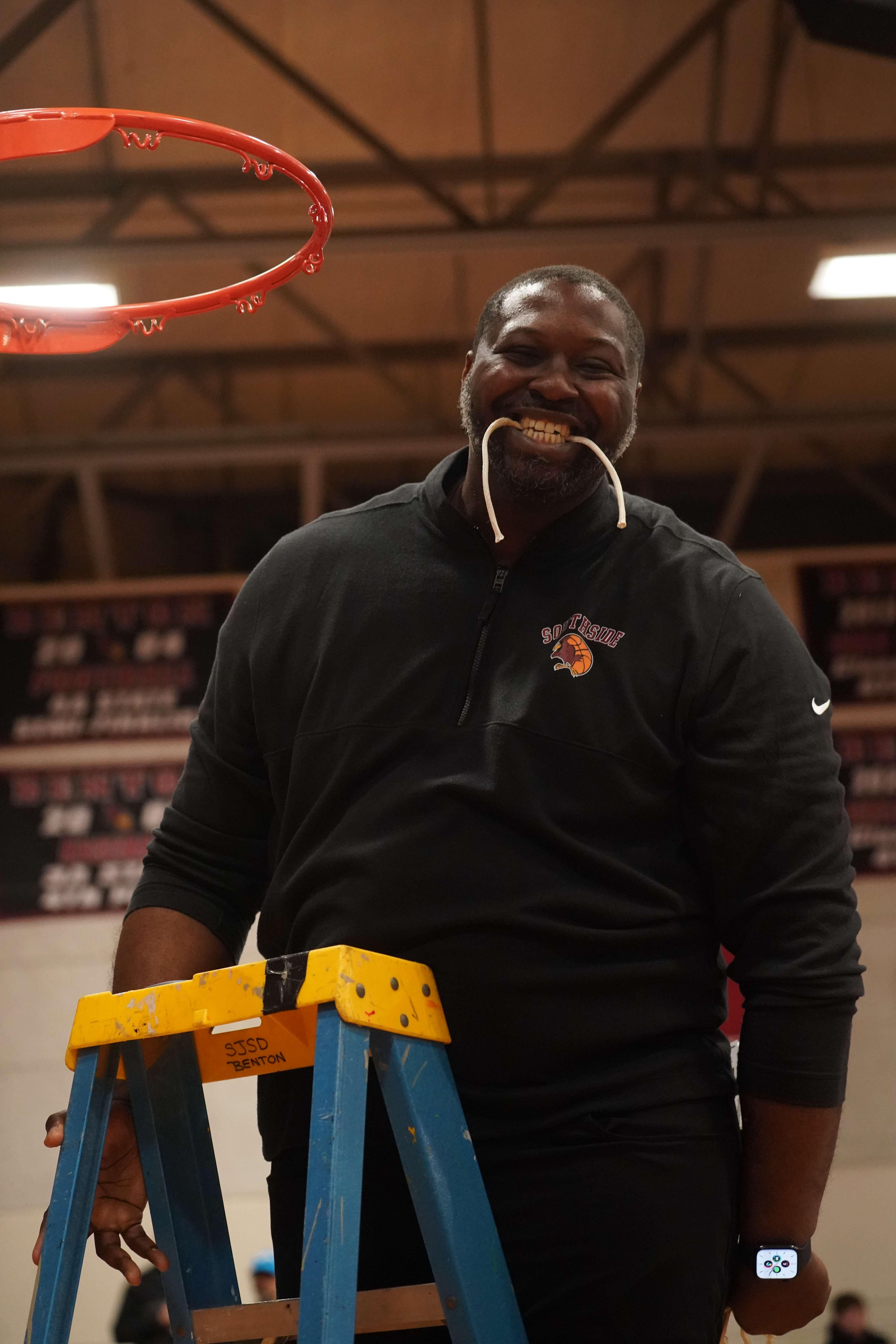 Head coach Jared Boone celebrates cutting down the net.&nbsp; Boone has led Benton, his alma mater, to back to back state tournaments and has had quite the run since becoming the head coach in 2021 leading the Cardinals to a 106-36 record/ Photo courtesy of Clifton Grooms