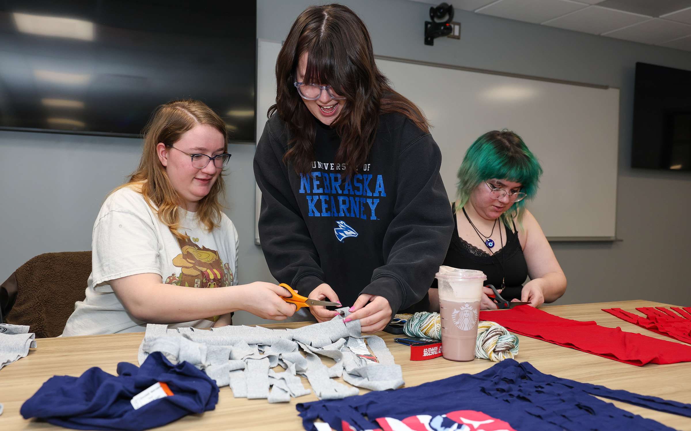 UNK junior Julia McKlem, center, leads an activity during a recent Crochet Circle meeting, where members created yarn from old T-shirts. McKlem started the student organization last year and serves as president. (Photo by Erika Pritchard, UNK Communications)