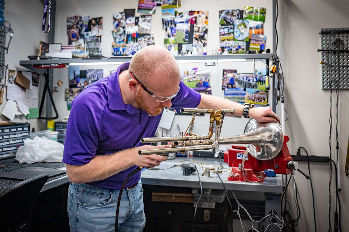 Using a tool to balance the horn, Colby Johnston, a senior in mechanical and nuclear engineering and student in an instrument repair class, sodders a brace onto a trombone he is restoring. (Photos by Jeff Moore/Kansas State University).