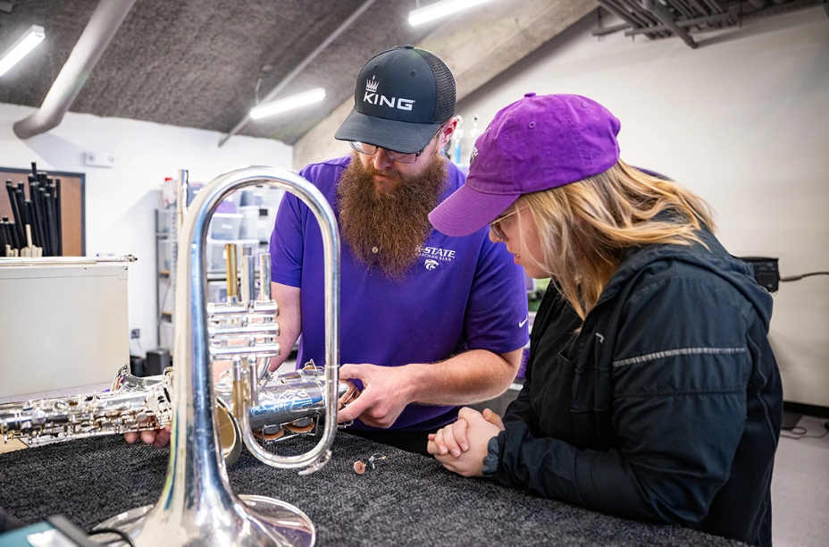 Joshua Cook and Kylee Gardner, a student in music business administration, examine a saxophone for leaks and issues as part of the instrument repair process.