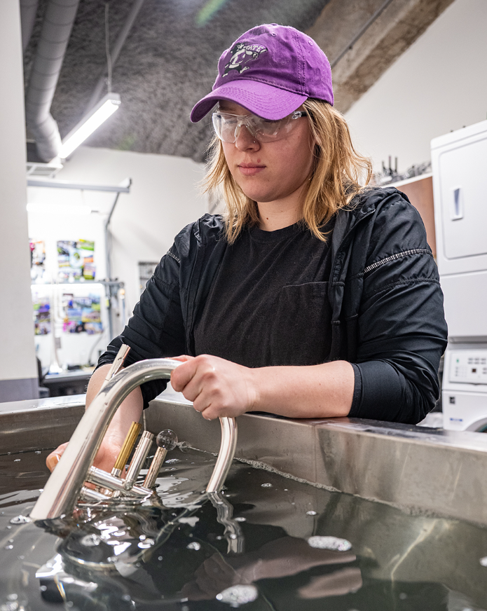 Kylee Gardner pulls a melophone out of the instrument repair workshop's ultrasonic cleaner. (Photo courtesy K-State News and Communications)