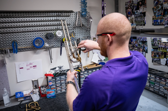 Colby Johnston checks the spacing on a brace he is using to repair a trombone. (Photo courtesy K-State News and Communications)
