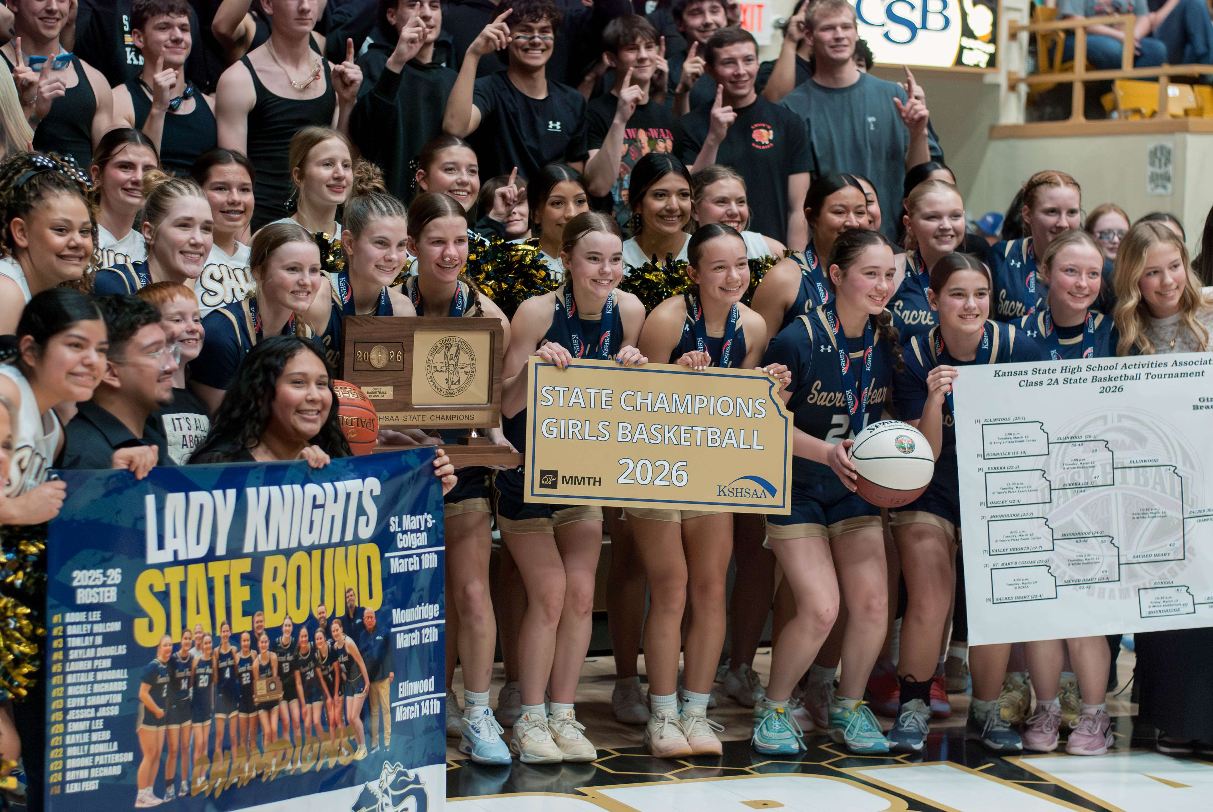 The Lady Knights proudly display their 2A state trophy in front of the Sacred Heart student section. Photo by Trae Toelle.