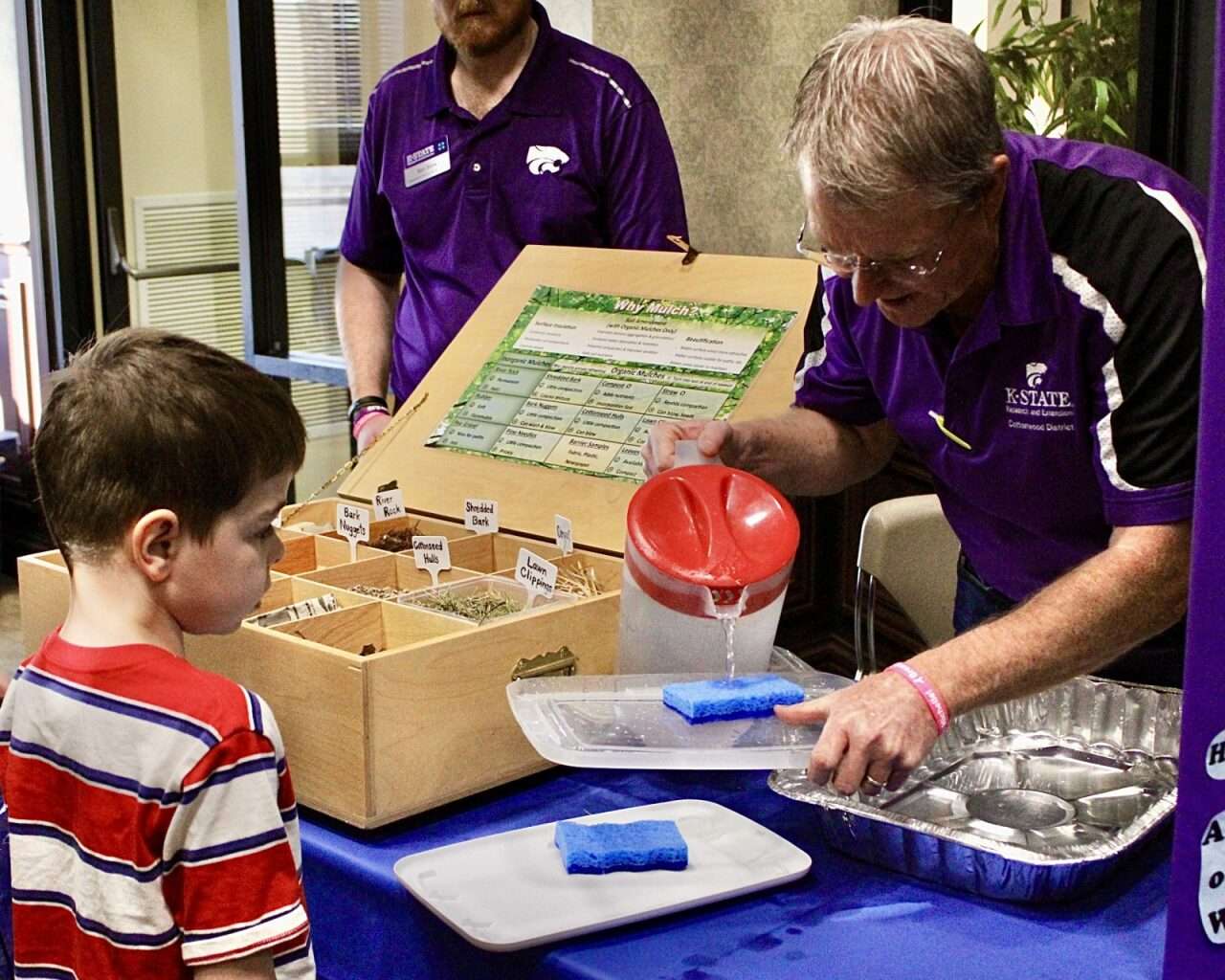 An attendee at the 2026 World Water Day Fun Fest being shown a water demonstration with a sponge. Photo by Tony Guerrero/Hays Post