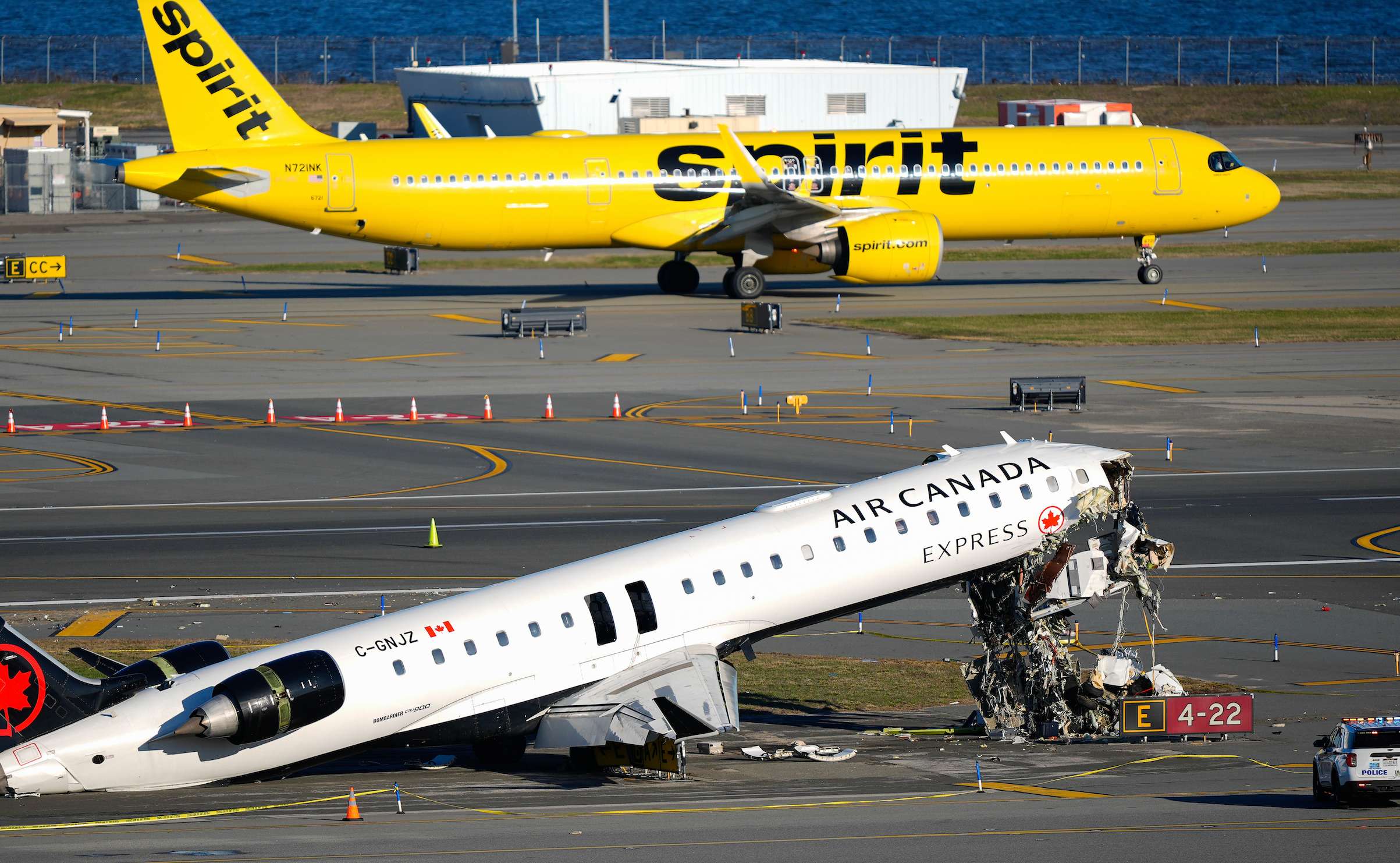 A Spirit Airlines jet taxis past an Air Canada Express jet sitting on the side of a runway, Tuesday, March 24, 2026, where it had collided with a Port Authority fire truck Sunday night at LaGuardia Airport in New York. (AP Photo/Yuki Iwamura)
