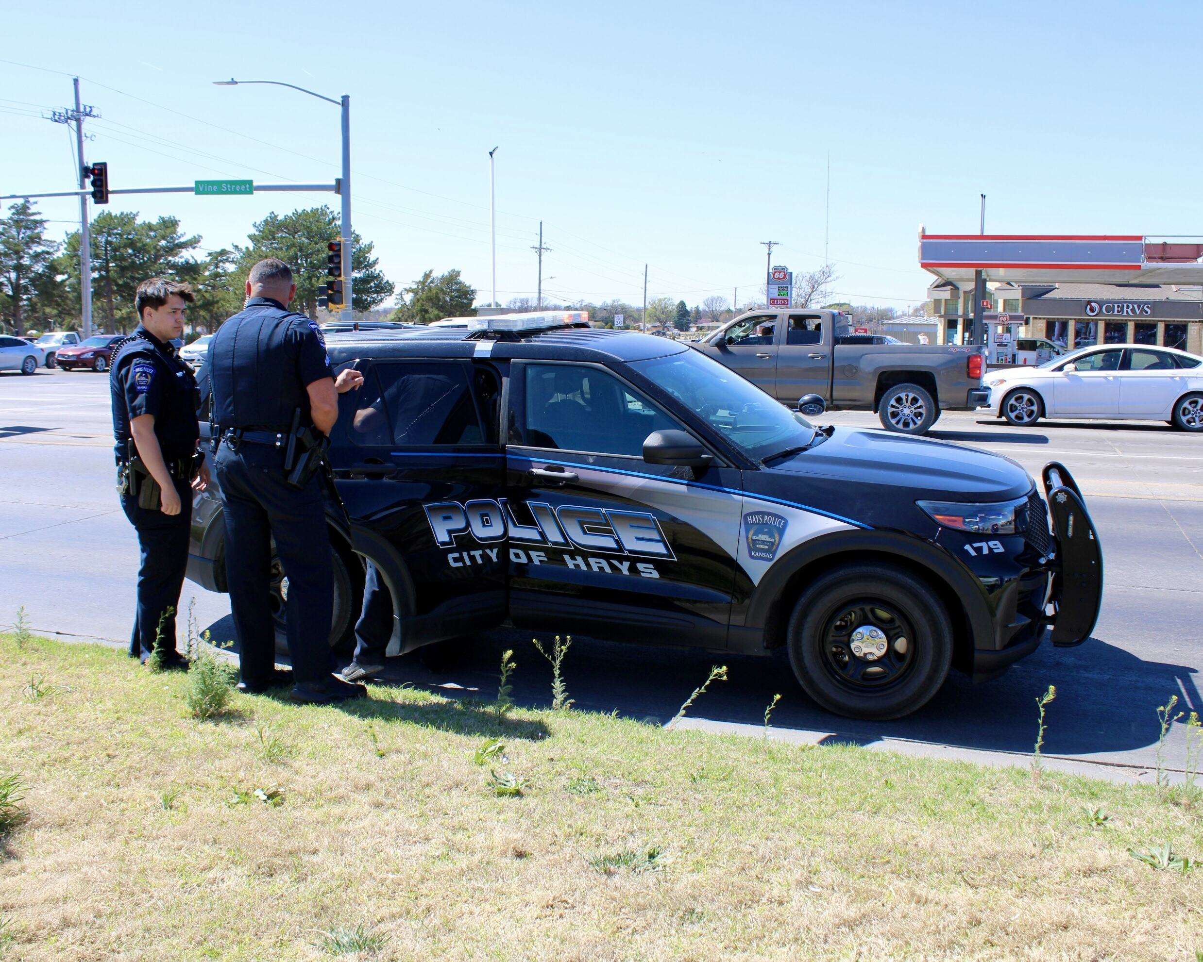 Responding Hays Police Department officers puting an unknown man in the back of a patrol car at the 'No Kings' protest on Saturday on the corner of 27th and Vine streets in Hays. Photo by Tony Guerrero/Hays Post