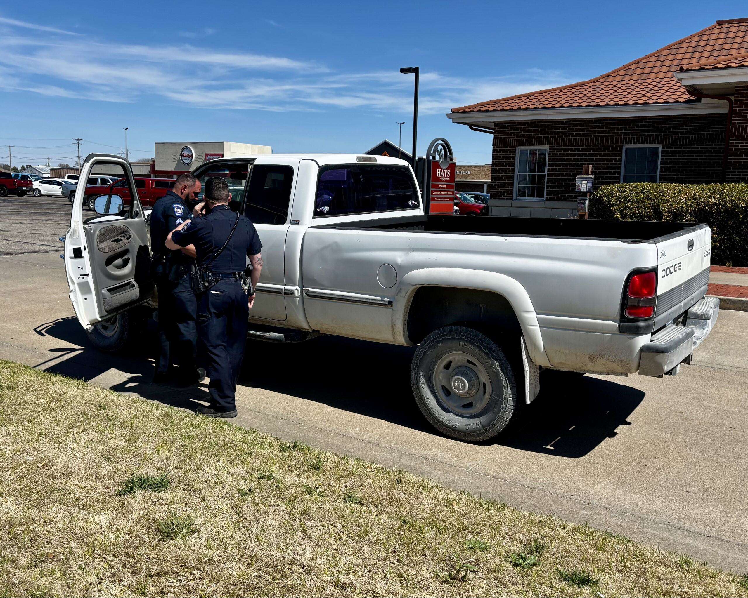 Hays officers at the unknown man's vehicle in front of the Hays Convention &amp; Visitors Bureau office. Photo by Tony Guerrero/Hays Post
