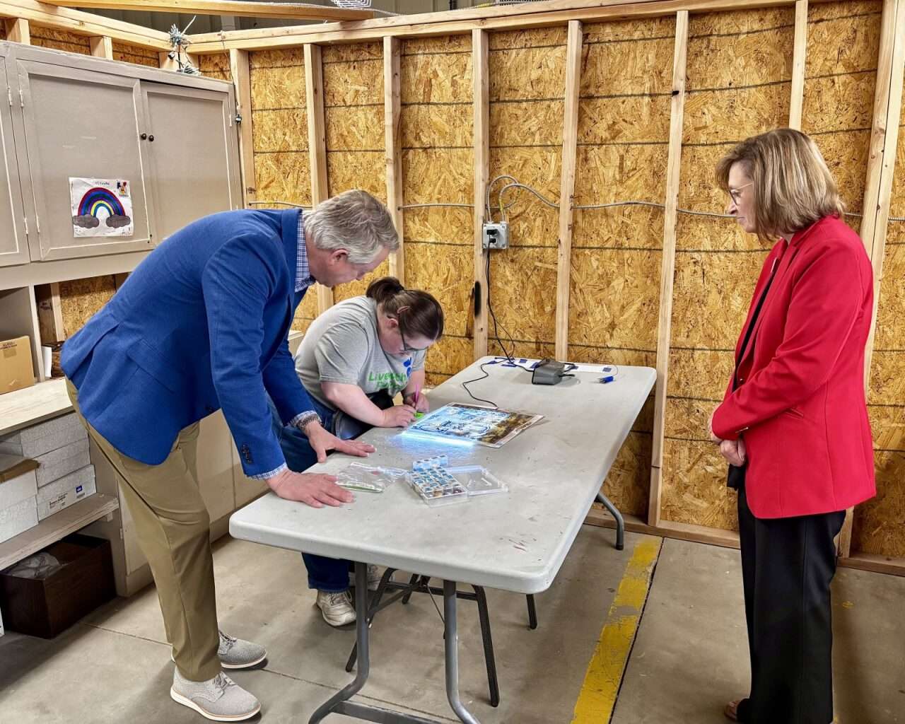 U.S. Sen. Roger Marshall and LaVonne Giess, DSNWK manager of employment, with an employee working on diamond art. Photo by Tony Guerrero/Hays Post