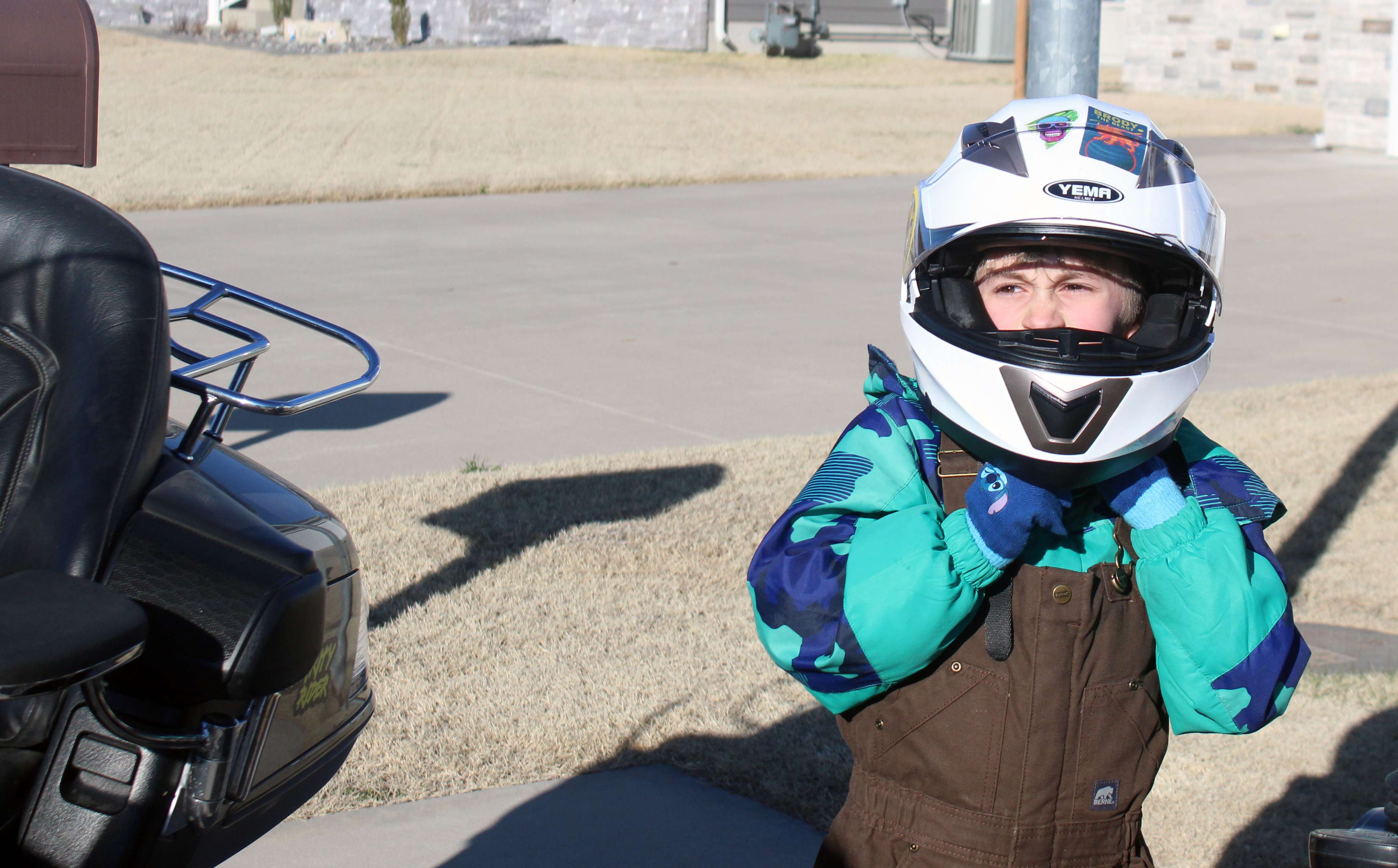 Brody adjusts his helmet as he gets ready to go for a ride with Dooley on his motorcycle. Photo by Cristina Janney/Hays Post