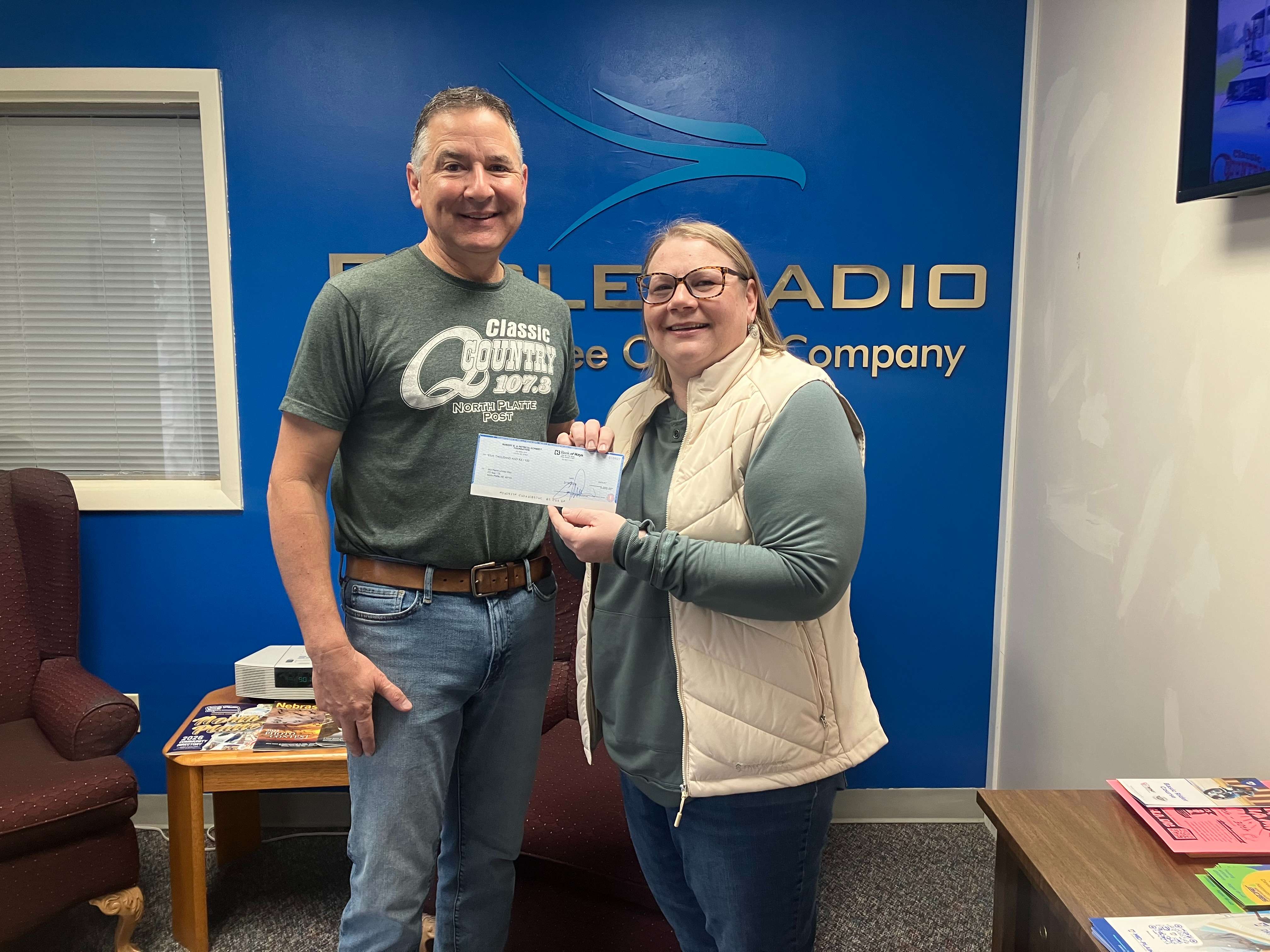 Lewys Carlini, with Eagle Media on behalf of the Schmidt Foundation, presents Kirsten Parker of Mid Plains United Way with a check for $5,000 to be designated to fire relief efforts for those affected by the Cottonwood Fire in west-central Nebraska.