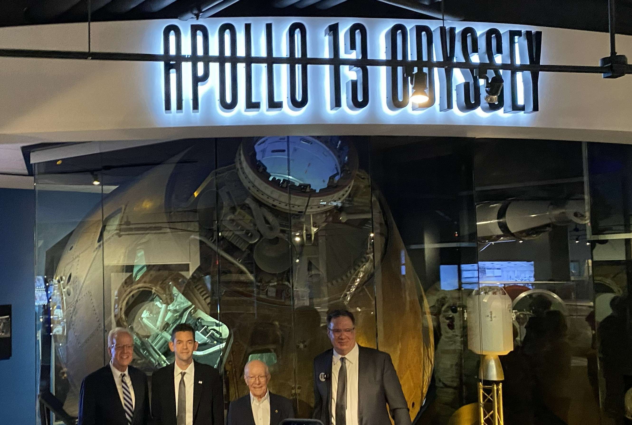 Senator Jerry Moran, NASA Administrator Jared Issacman, Apollo Flight Director Gerry Griffin and Cosmosphere CEO Jim Remar are dwarfed by the Apollo 13 Odyssey capsule on April 6, 2025. (Hutch Post Photo) 