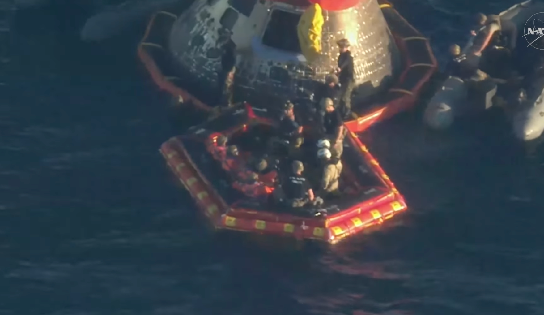 All four astronauts (orange jumpsuits) out of the spacecraft -image from NASA video