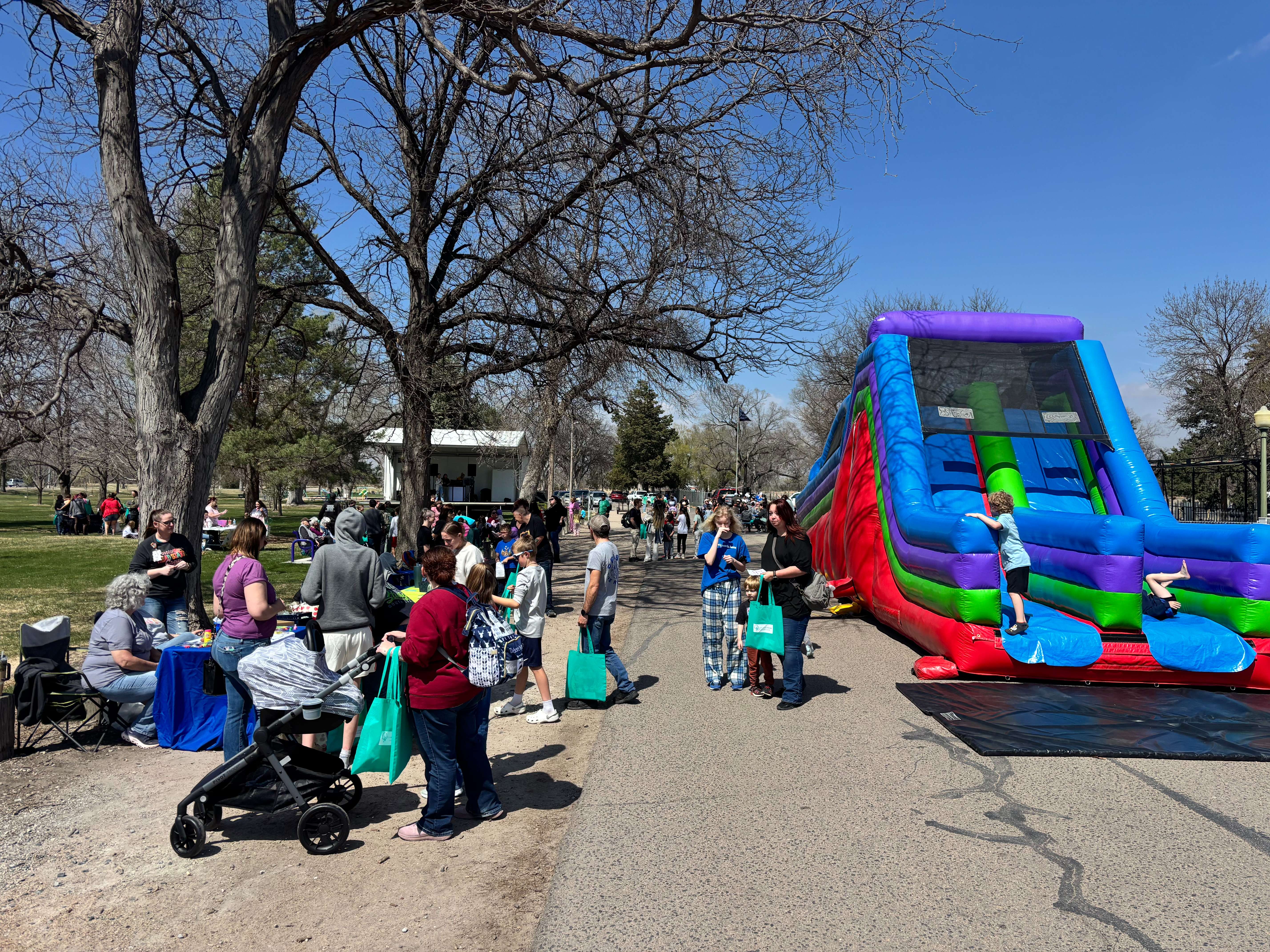 Children take turns on a popular inflatable slide while families explore booths and activities during Kids in the Park in North Platte. (The Post)