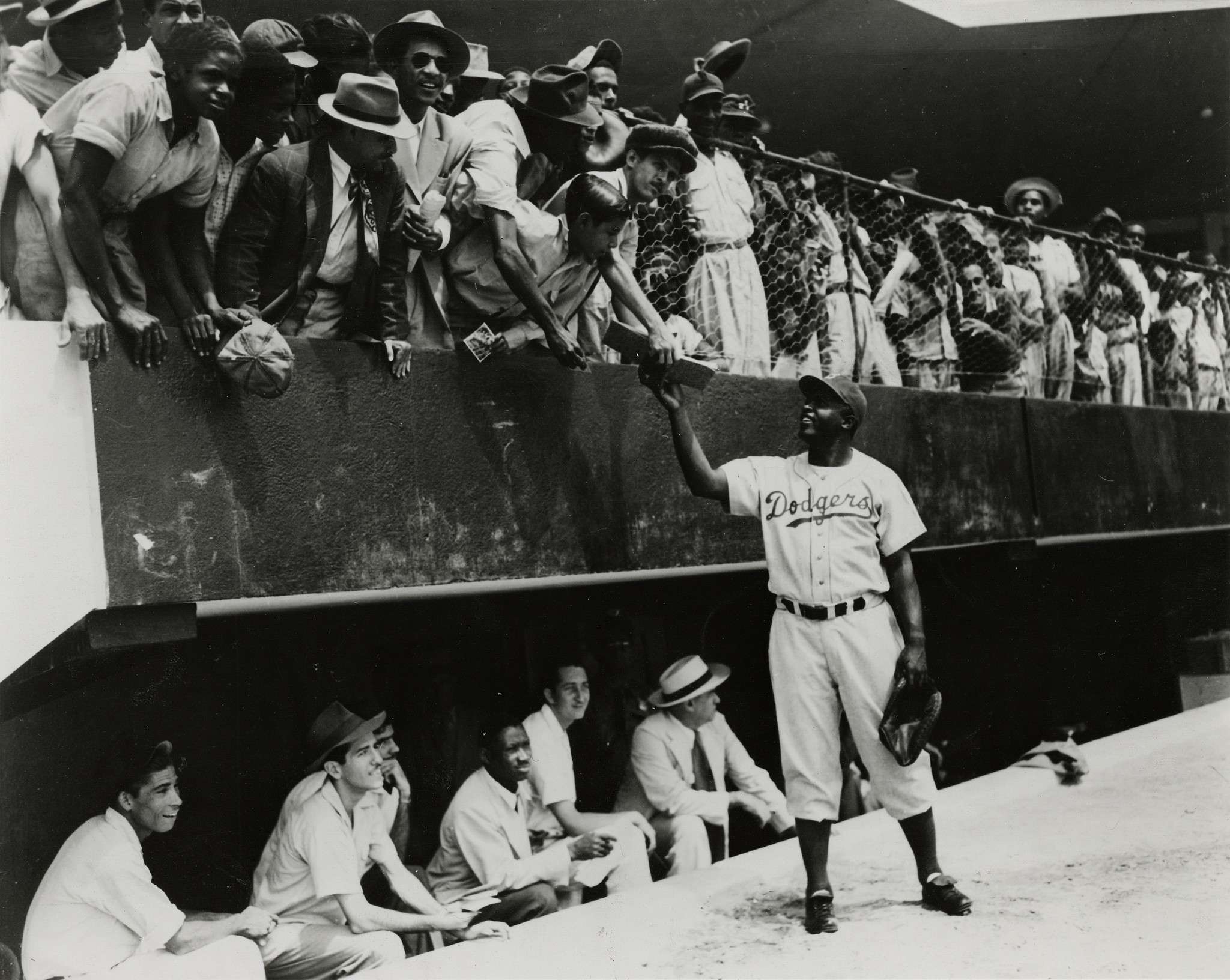 Jackie Robinson, first baseman of the Brooklyn Dodgers, returns an autograph book to a fan in the stands, during the Dodgers' spring training in Ciudad Trujillo, now Santo Domingo, in the Dominican Republic, on March 6, 1948. (AP Photo/File)