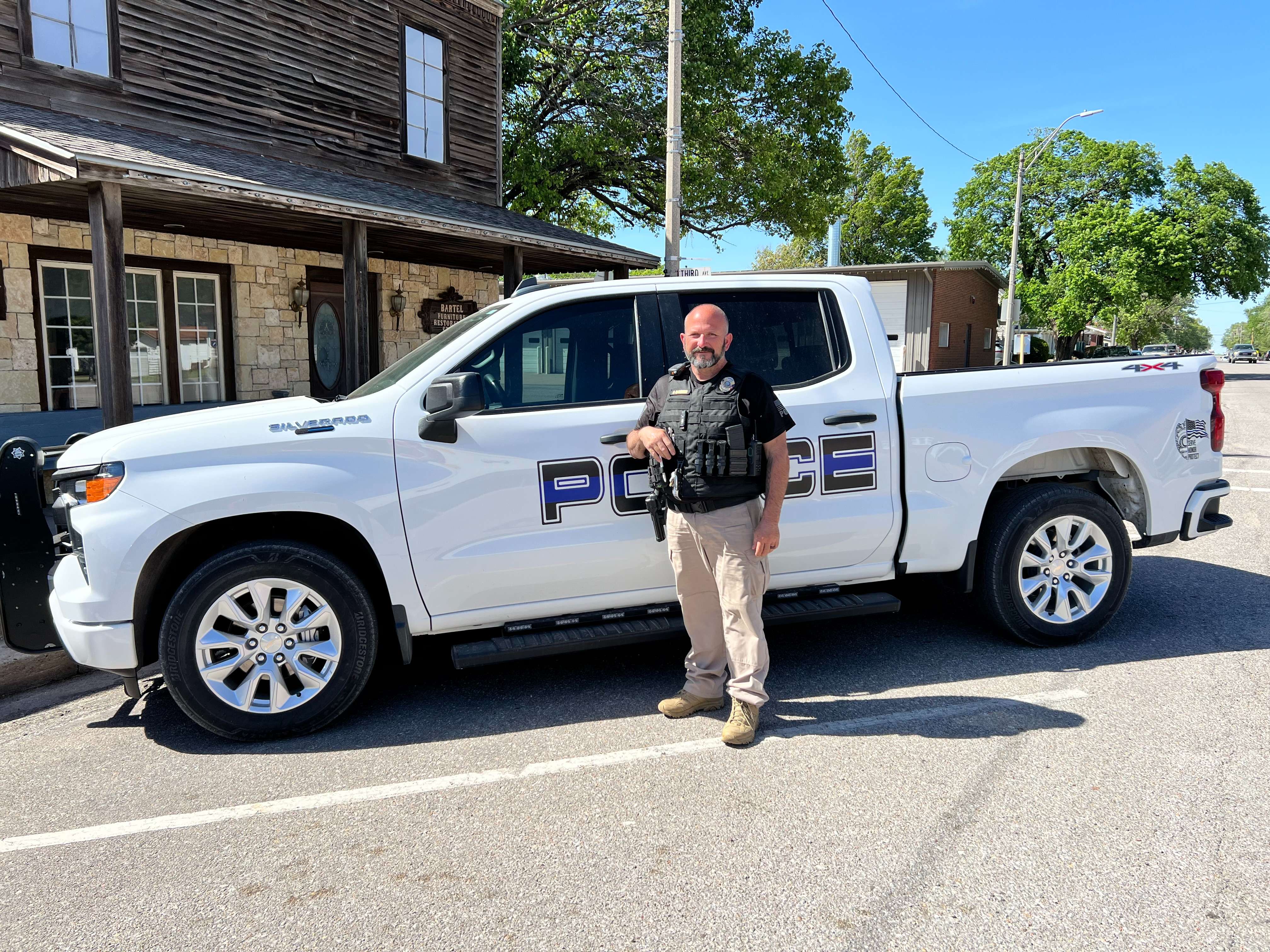 Buhler Police Department Captain Anthony Baldwin poses for a photo with his patrol vehicle in downtown Buhler. Baldwin will retire April 30 after 32 years with the Buhler Police Department. (Hutch Post Photo/Sean Boston)