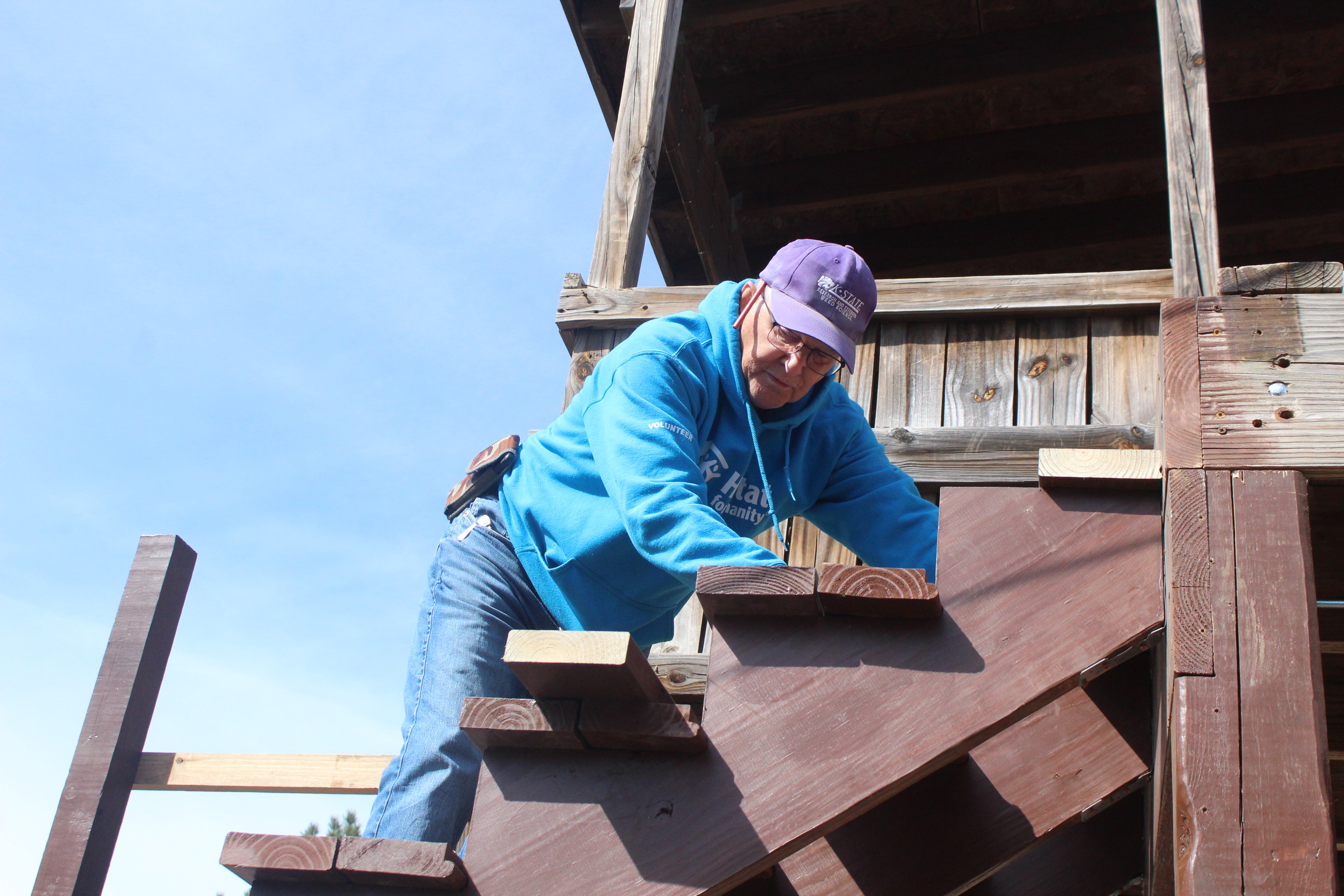 Phil Stahlman, Habitat volunteer and project leader, places a board during a stair repair project in March. Stahlman also volunteers regularly at the Habitat ReStore resale shop in Hays. Photo by Cristina Janney/Hays Post<br>
