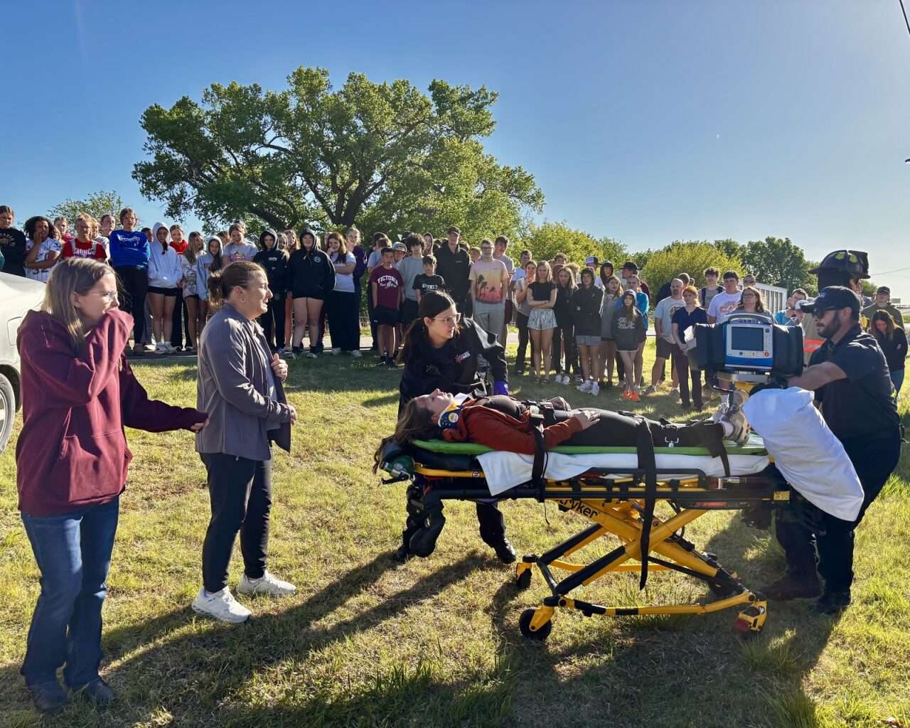 The injured driver on a stretcher with her distraught family members, also part of the demonstration. Victoria High School students look on. Photo by Tony Guerrero/Hays Post