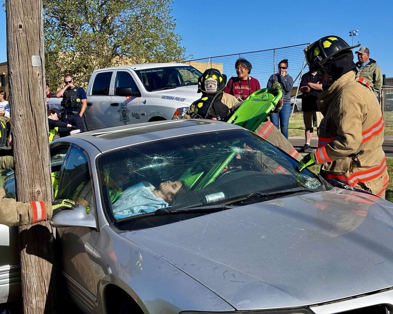 A student acting as an unresponsive victim of the simulated two-vehicle crash, with firefighters attempting to remove her from the car. Photo by Tony Guerrero/Hays Post