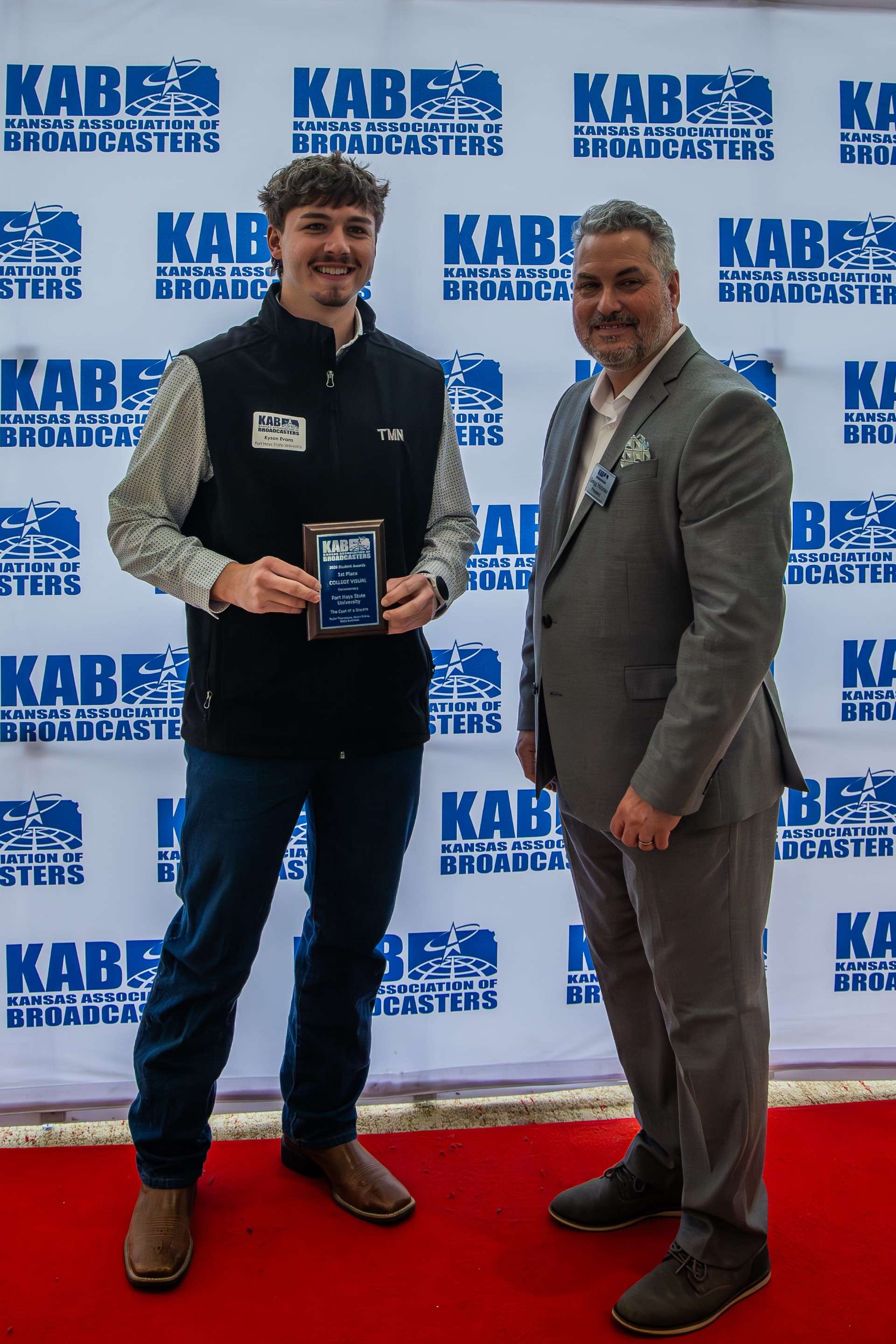 Kyson Evans accepts the first-place plaque for documentary from Gregg Hibbeler, president of the Kansas Association of Broadcasters, during the April 9 awards ceremony in Kansas City, Missouri.