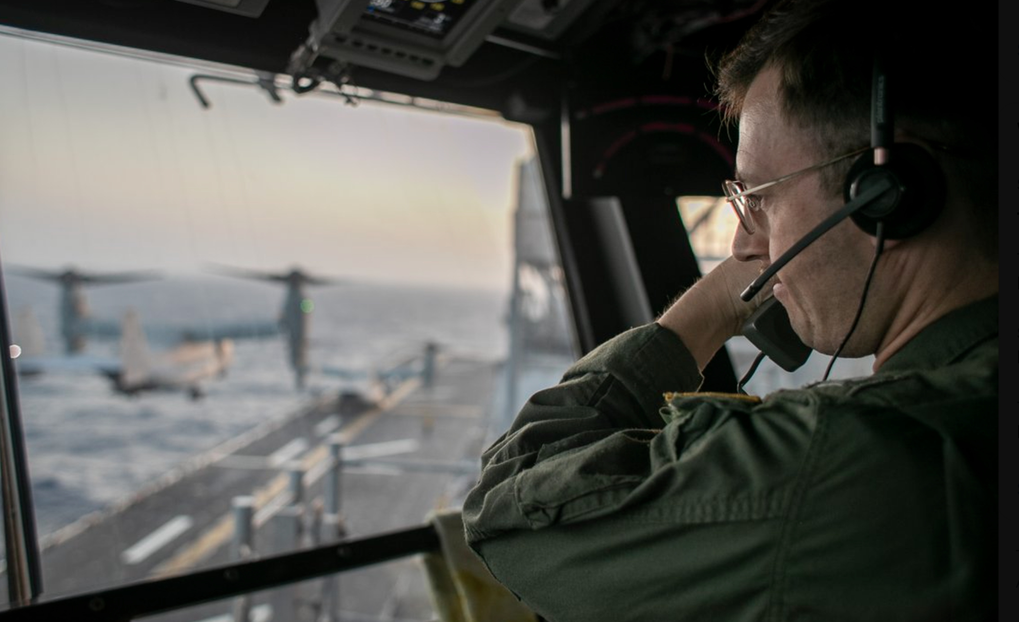A naval officer aboard USS Tripoli (LHA 7) oversees flight operations from the control tower as the amphibious assault ship sails in the Arabian Sea. U.S. warships and aircraft deployed to the Middle East are enforcing the naval blockade against Iran while executing Project Freedom to support the free flow of commerce through the Strait of Hormuz.