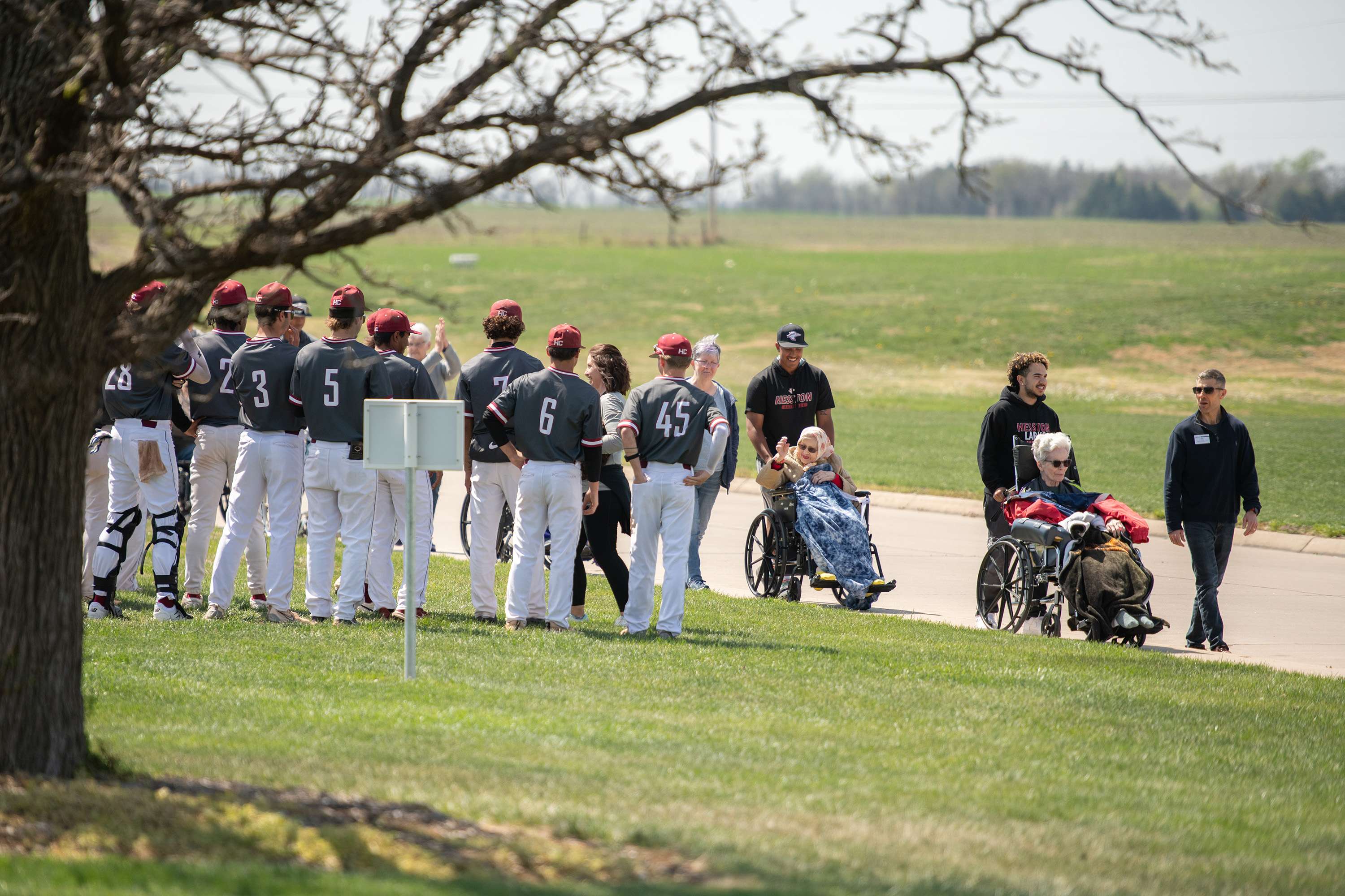  The Hesston College baseball team greets residents as they approach Oswald Field for a special Schowalter Villa baseball day in honor of the friendships built over the year. Photo by Larry Bartel, Hesston College.   