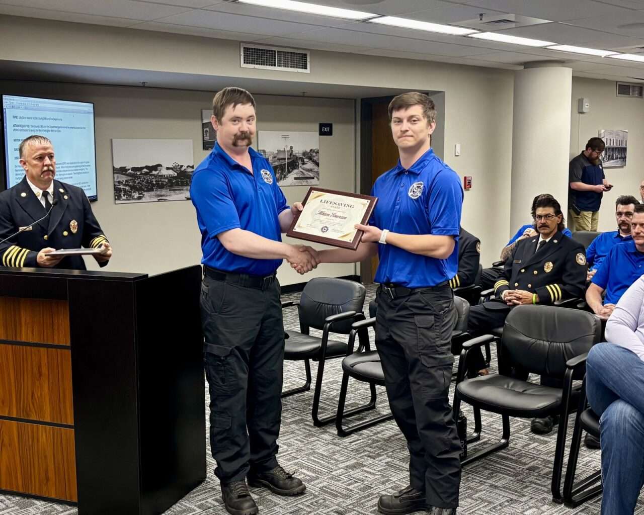 Firefighter Matt VanDyke handing firefighter Mason Emerson a Lifesaving Commendation Award. Photo by Tony Guerrero/Hays Post