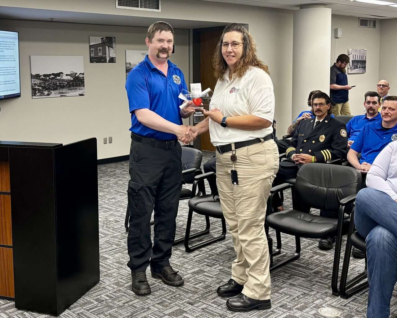Firefighter Matt VanDyke handing EMS Director Danita Schroeder an EMS Field Save Award.&nbsp; Photo by Tony Guerrero/Hays Post