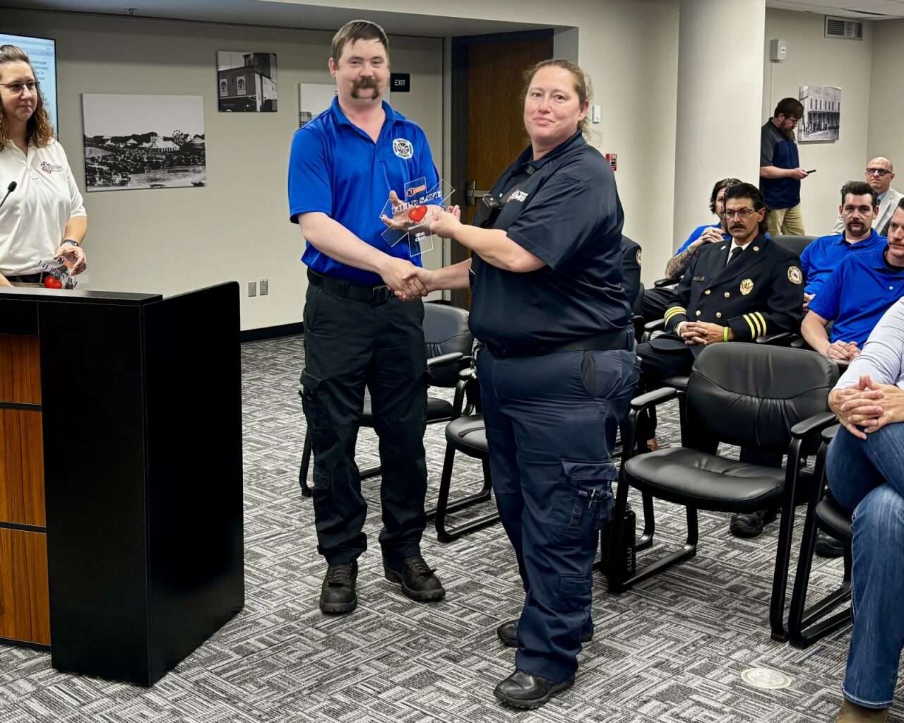Firefighter Matt VanDyke handing Capt. Elea Cook an EMS Field Save Award.&nbsp; Photo by Tony Guerrero/Hays Post