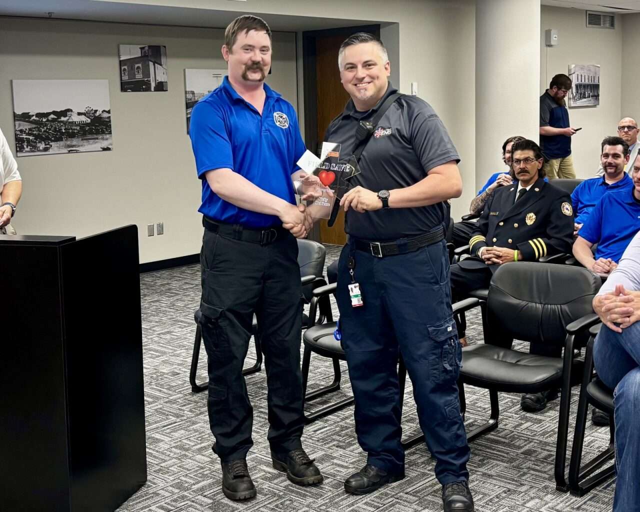 Firefighter Matt VanDyke handing paramedic Kelly Depiesse an EMS Field Save Award. Photo by Tony Guerrero/Hays Post