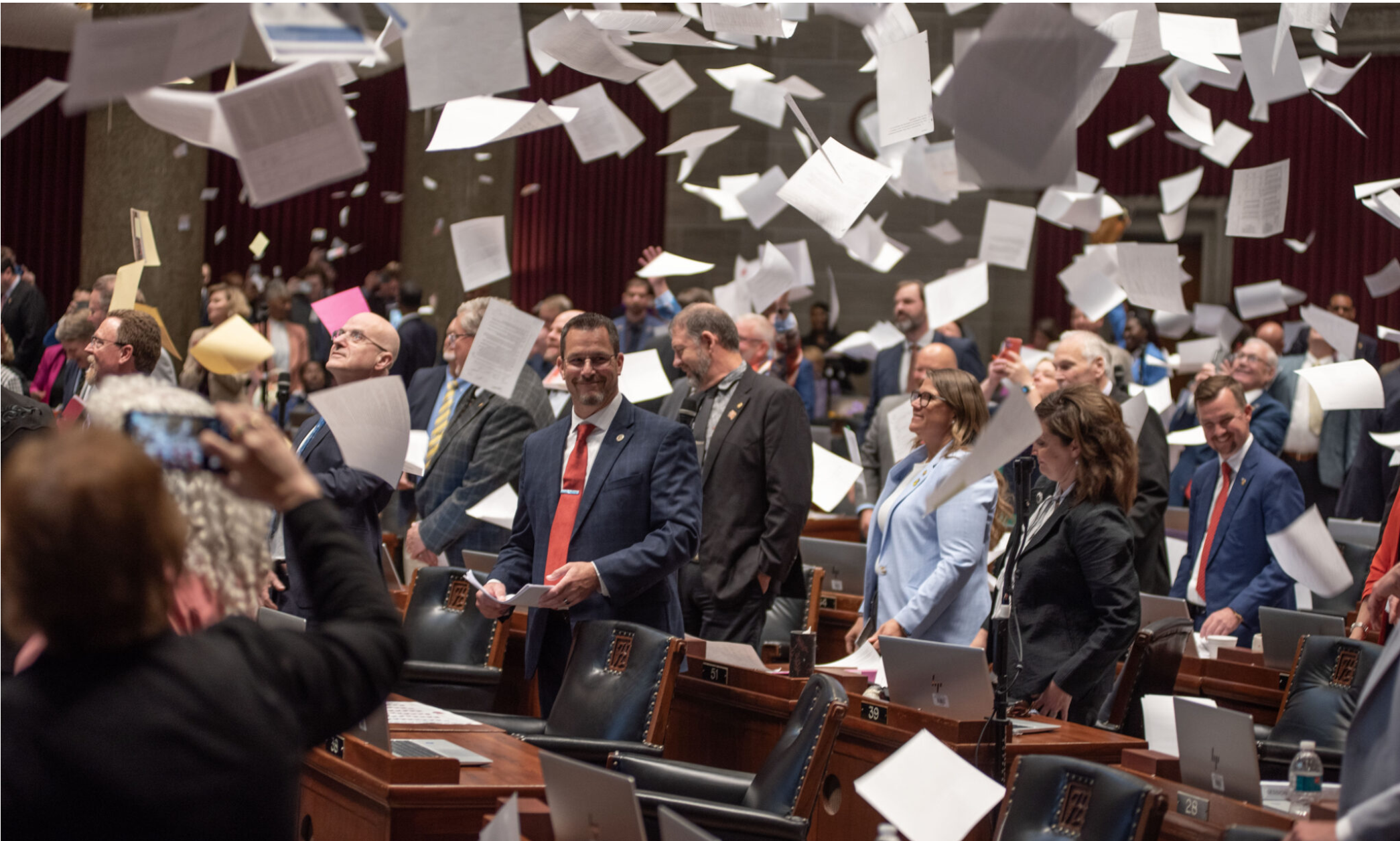  State Rep. Brandon Phelps, a Republican from Warrensburg, smiles as the Missouri House tosses bills into the air at the adjournment of session Friday (Annelise Hanshaw/Missouri Independent).