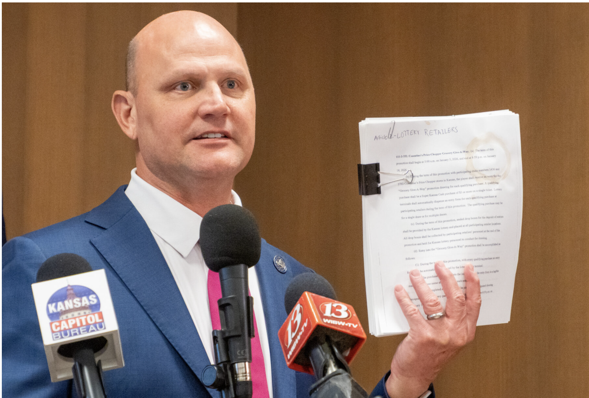 Kansas Secretary of State Scott Schwab illustrates problems with paper-based systems by showing a coffee-stained document during a press conference on May 19, 2025, at the Docking State Office Building. (Photo by Anna Kaminski/Kansas Reflector)