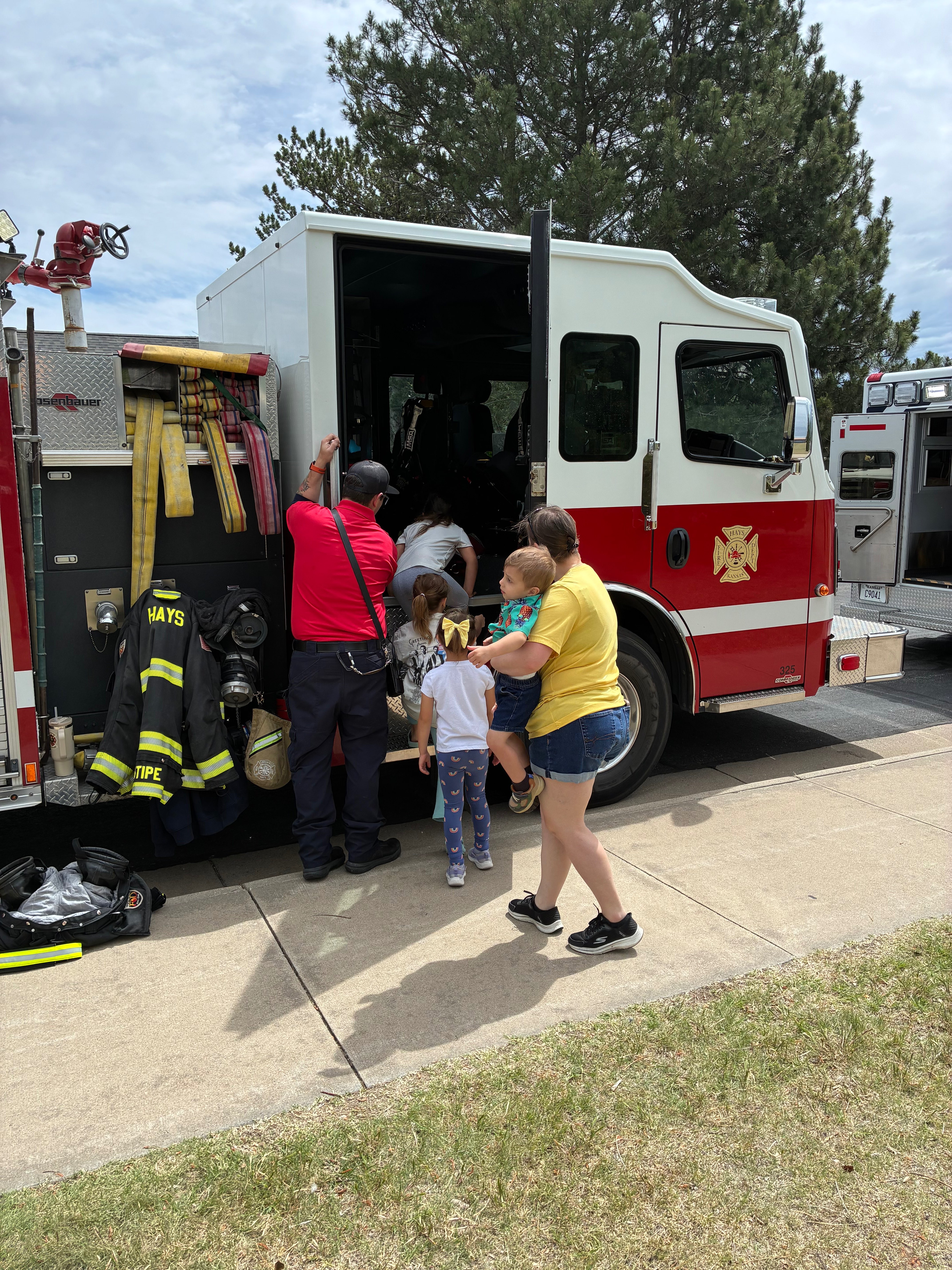 Hays Fire Department firefighter Faisal Miller gives children a tour of Fire Engine 3 allowing families to explore the fire truck up close. Photo by Alin Hett/Hays Post