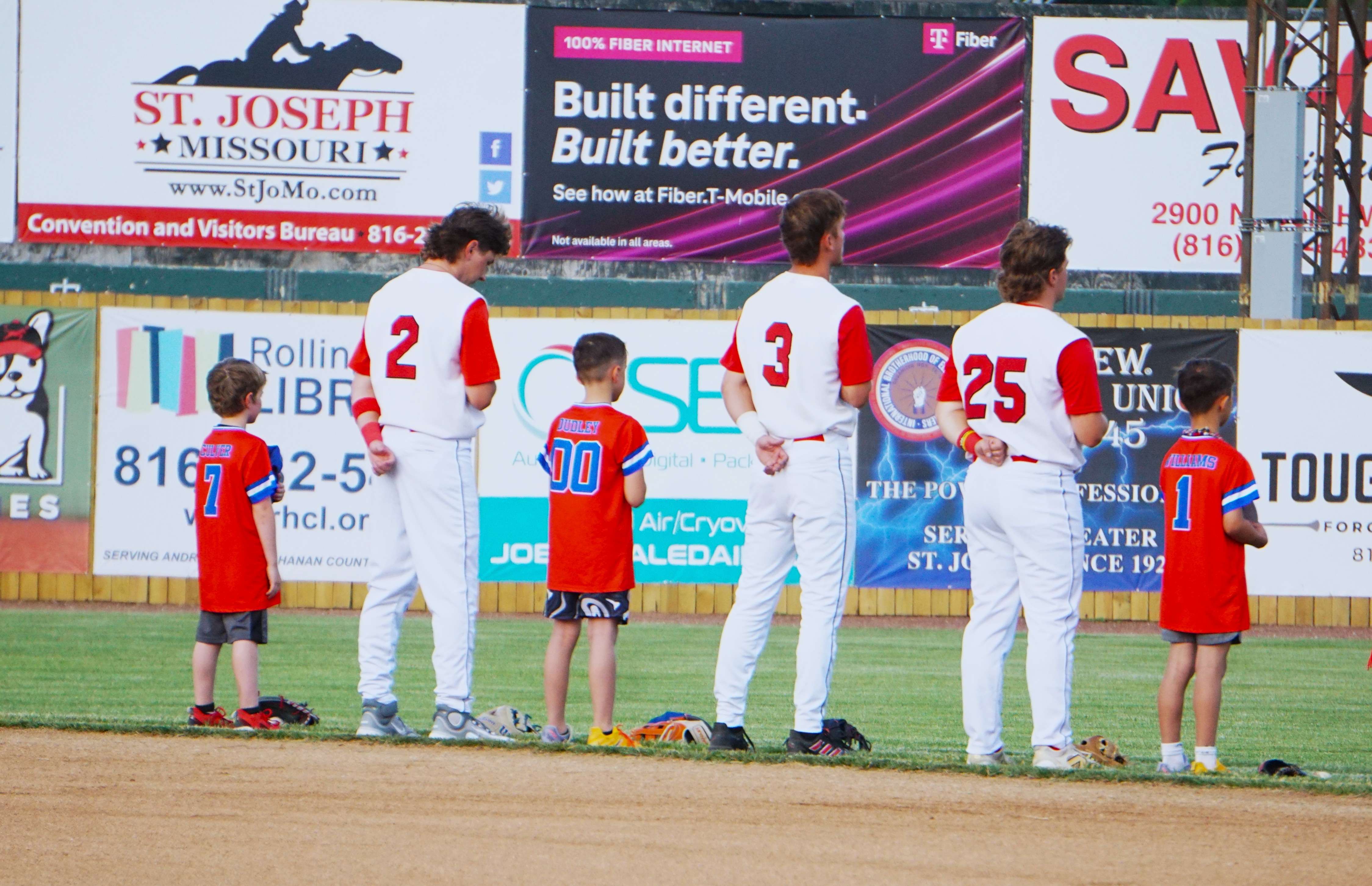 Eden Myers (2), Benton alum Chris Coy (3), and Missouri Western's Seth Winkler (25) stand with their buddies for the National Anthem during Mustangs Opening Day/ Photo by Matt Pike