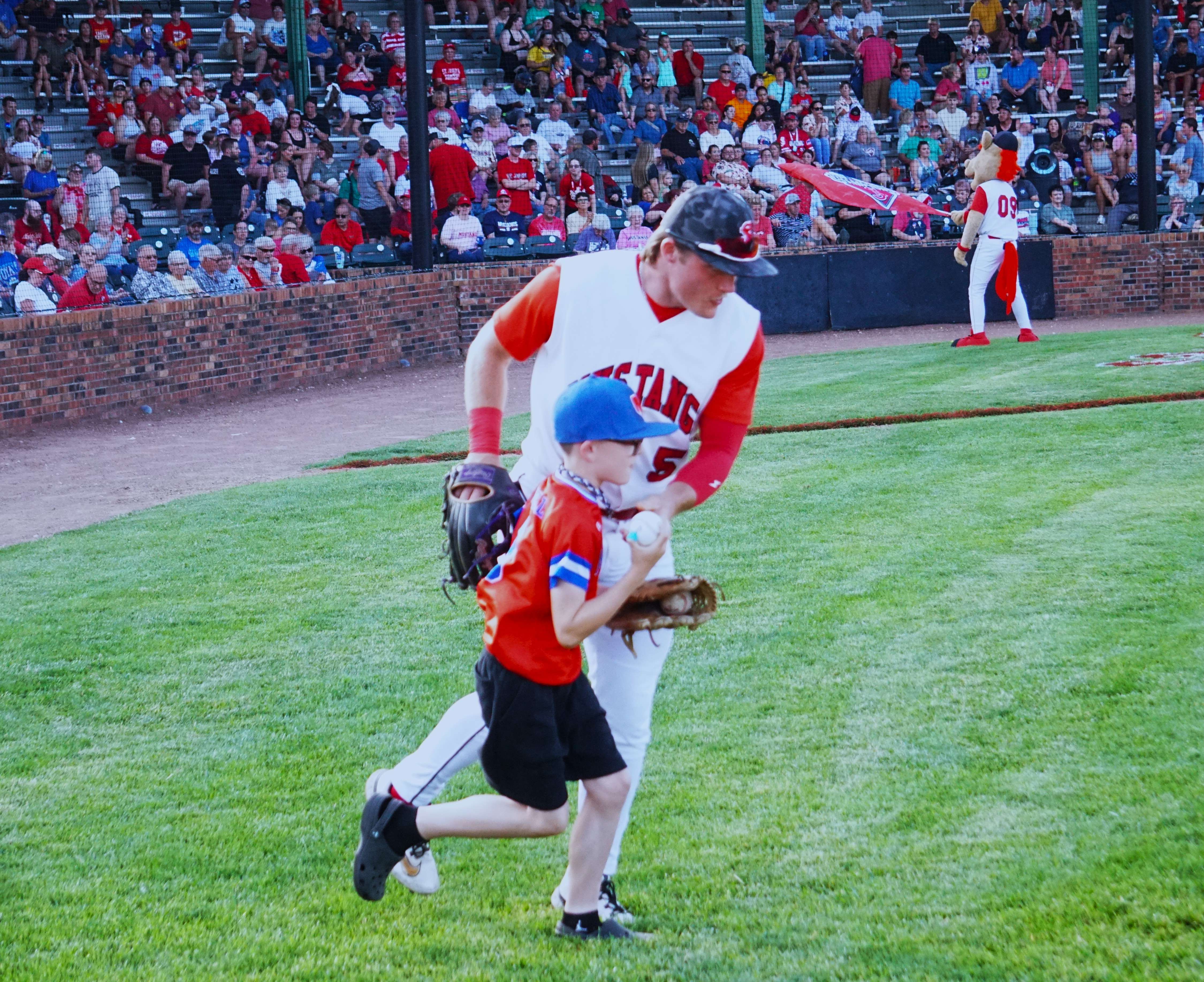 Mustangs center fielder and Missouri Western's Micah Kobuszewski takes the field with his buddy on Mustangs Opening Day/ Photo by Matt Pike