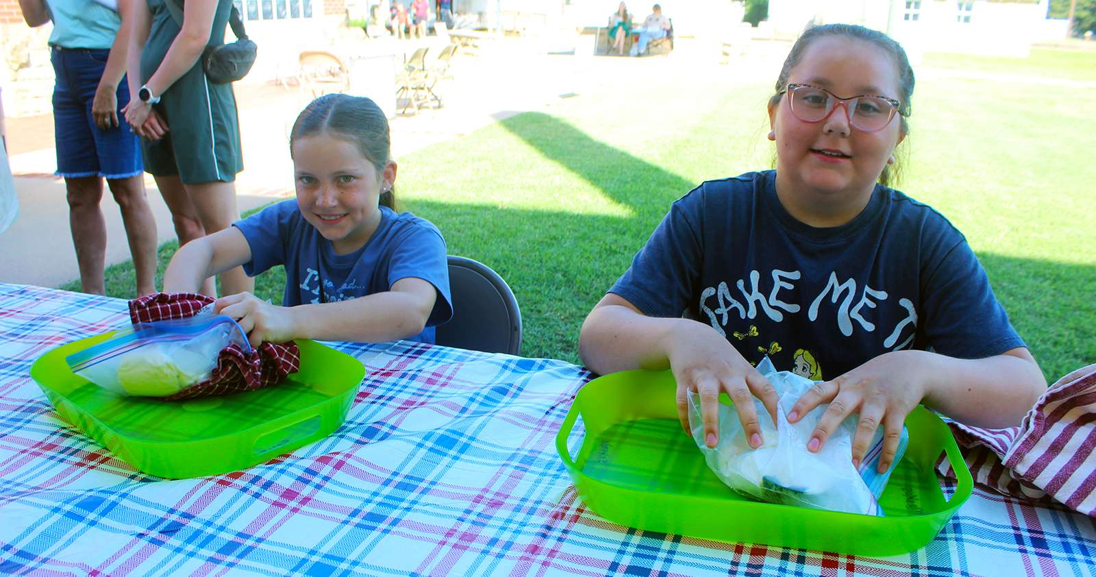 Two girls make ice cream by rolling a bag filled with cream and ice. Photo by Cristina Janney/Hays Post